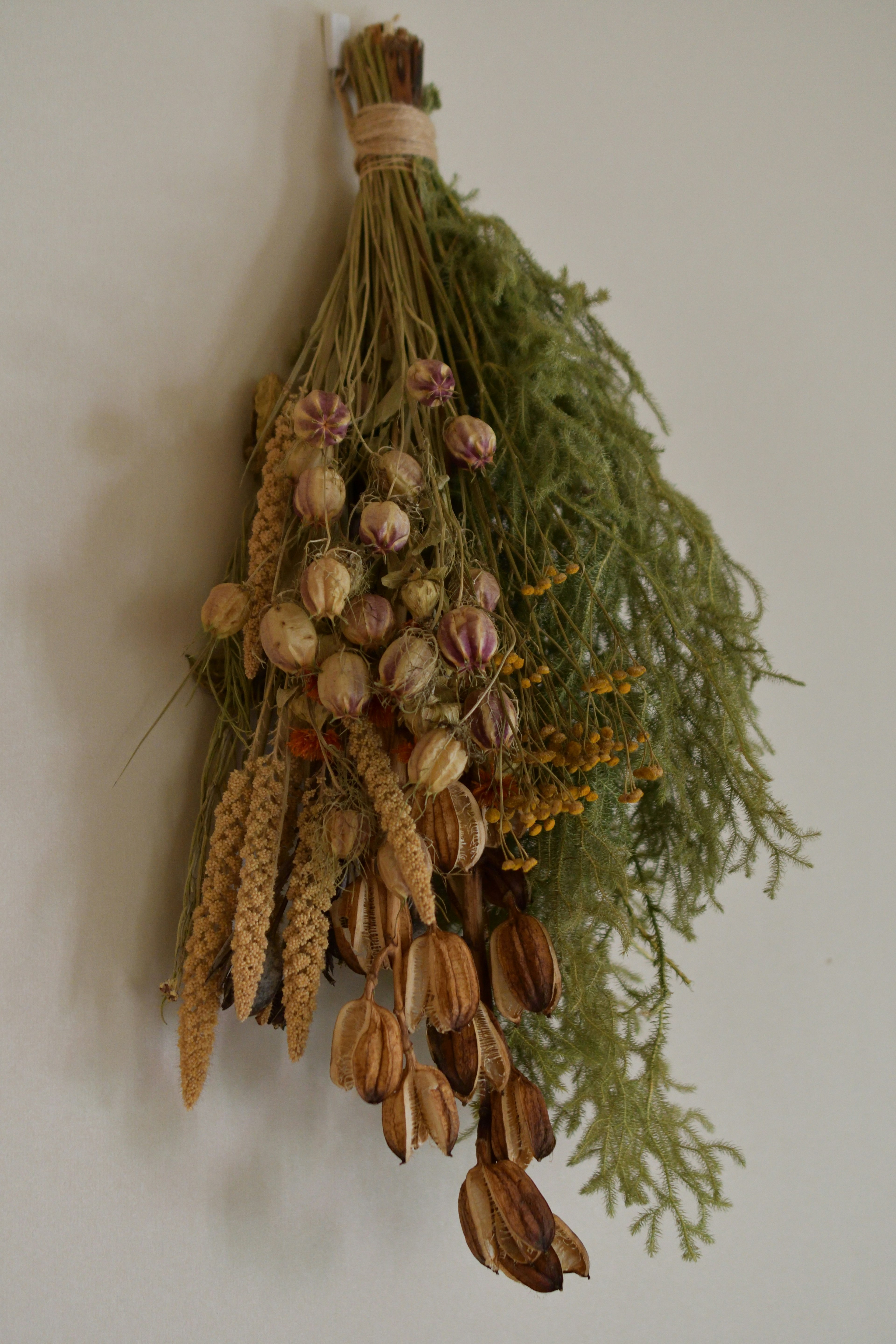 A bundle of dried herbs with green leaves and colorful dried flowers