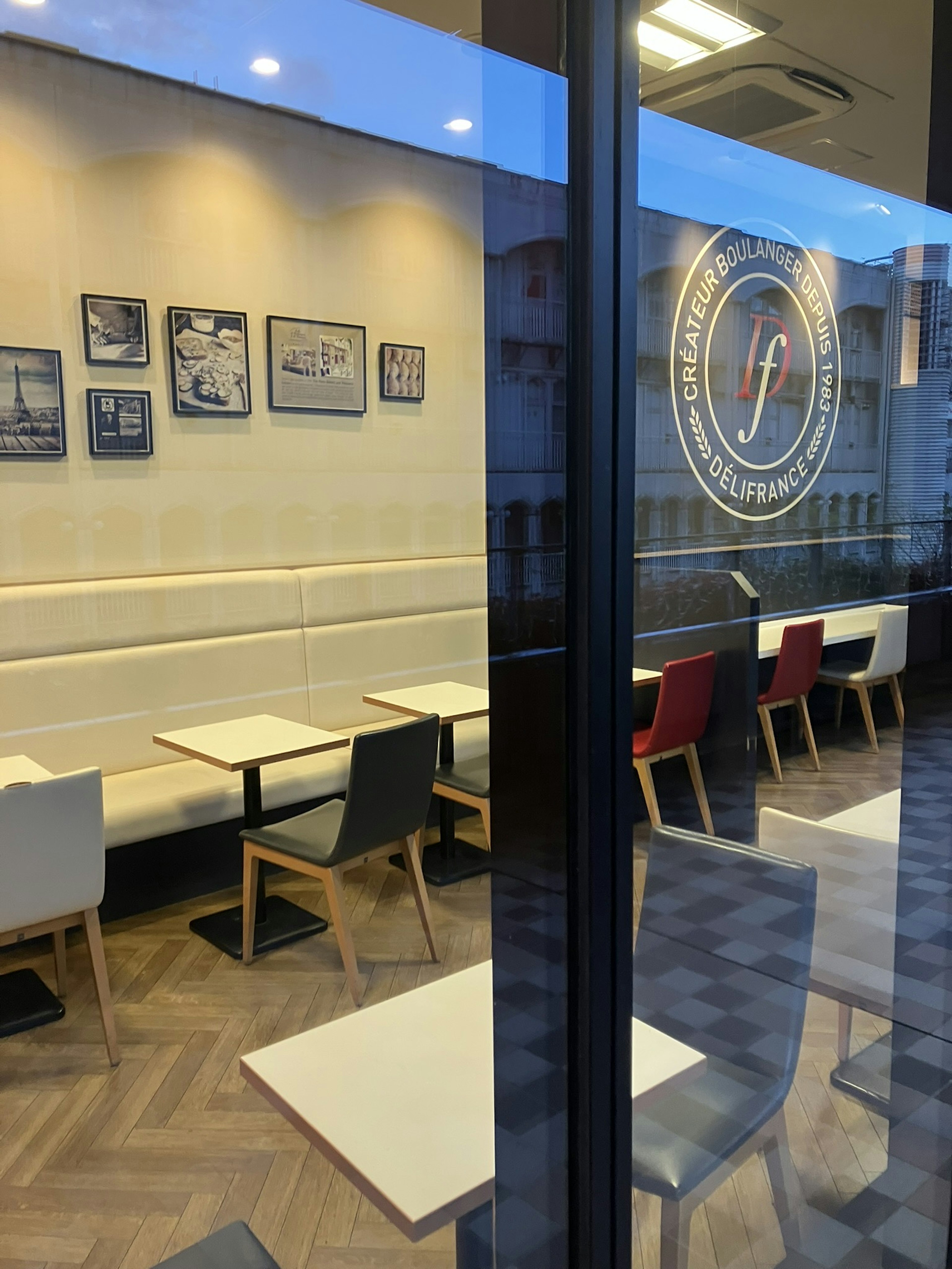 Interior view of a café through glass featuring white walls and framed photos