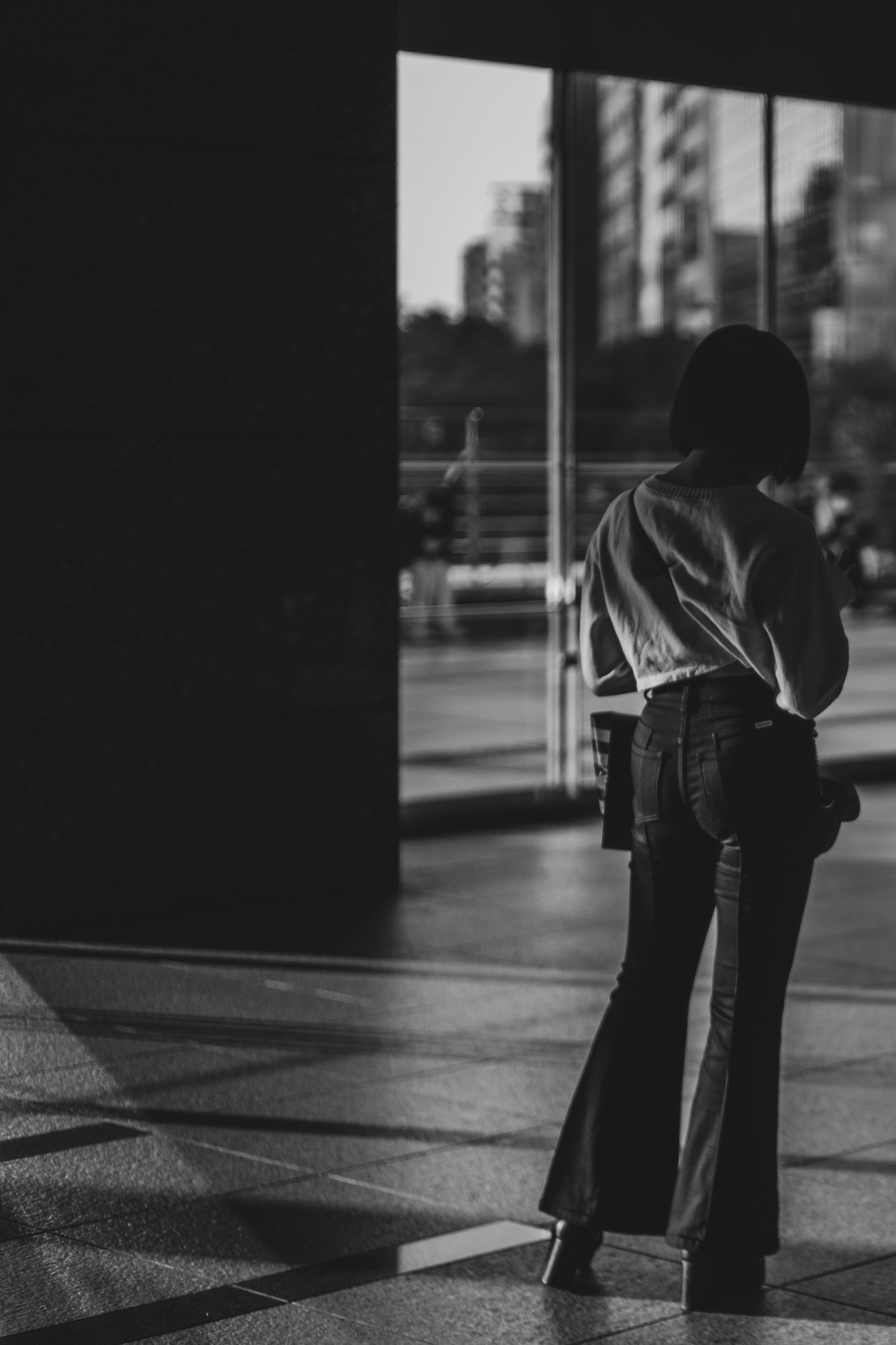 Silueta de una mujer de pie en un paisaje urbano con fuerte contraste en blanco y negro