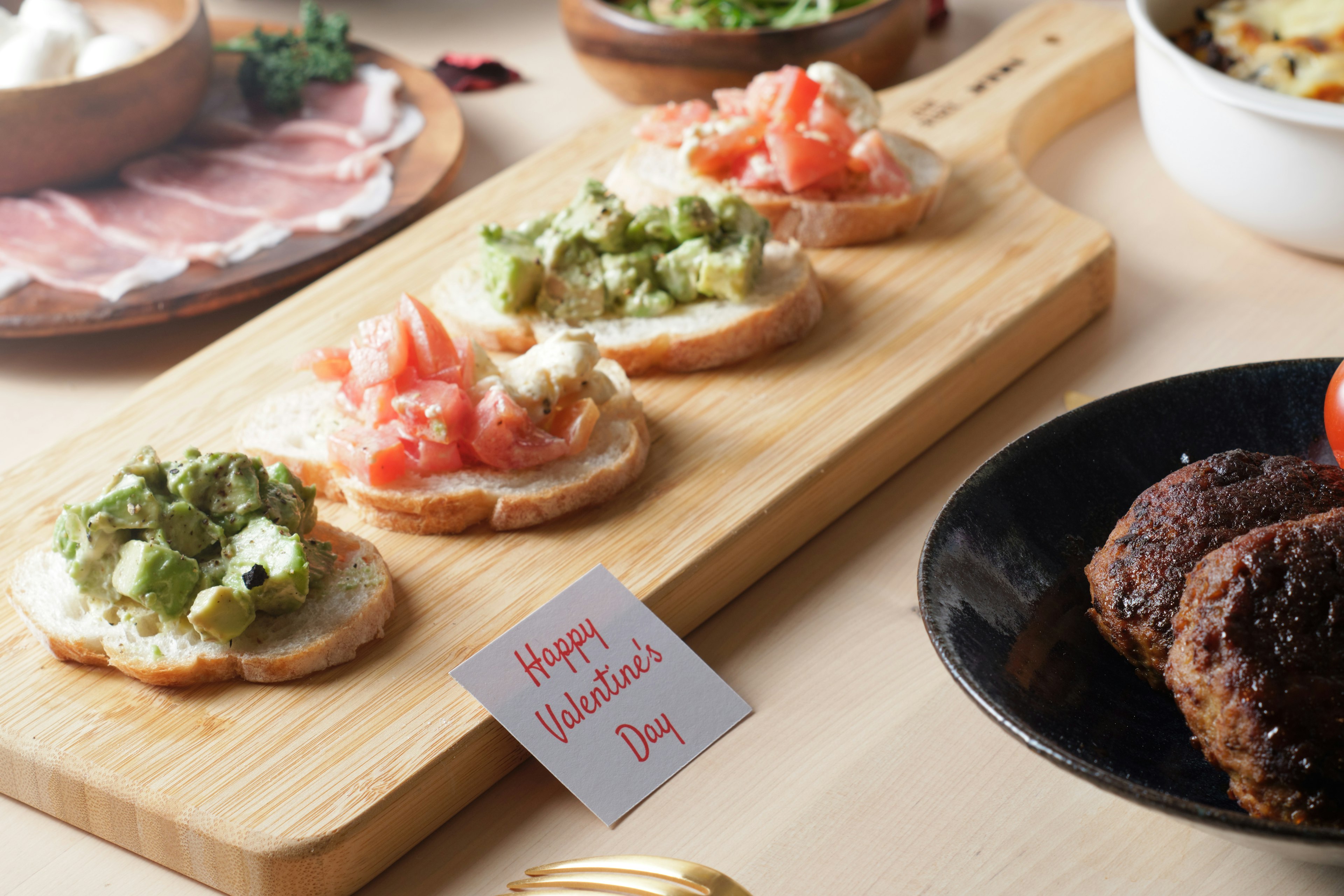 A table scene featuring appetizers on a wooden board with toast and ham