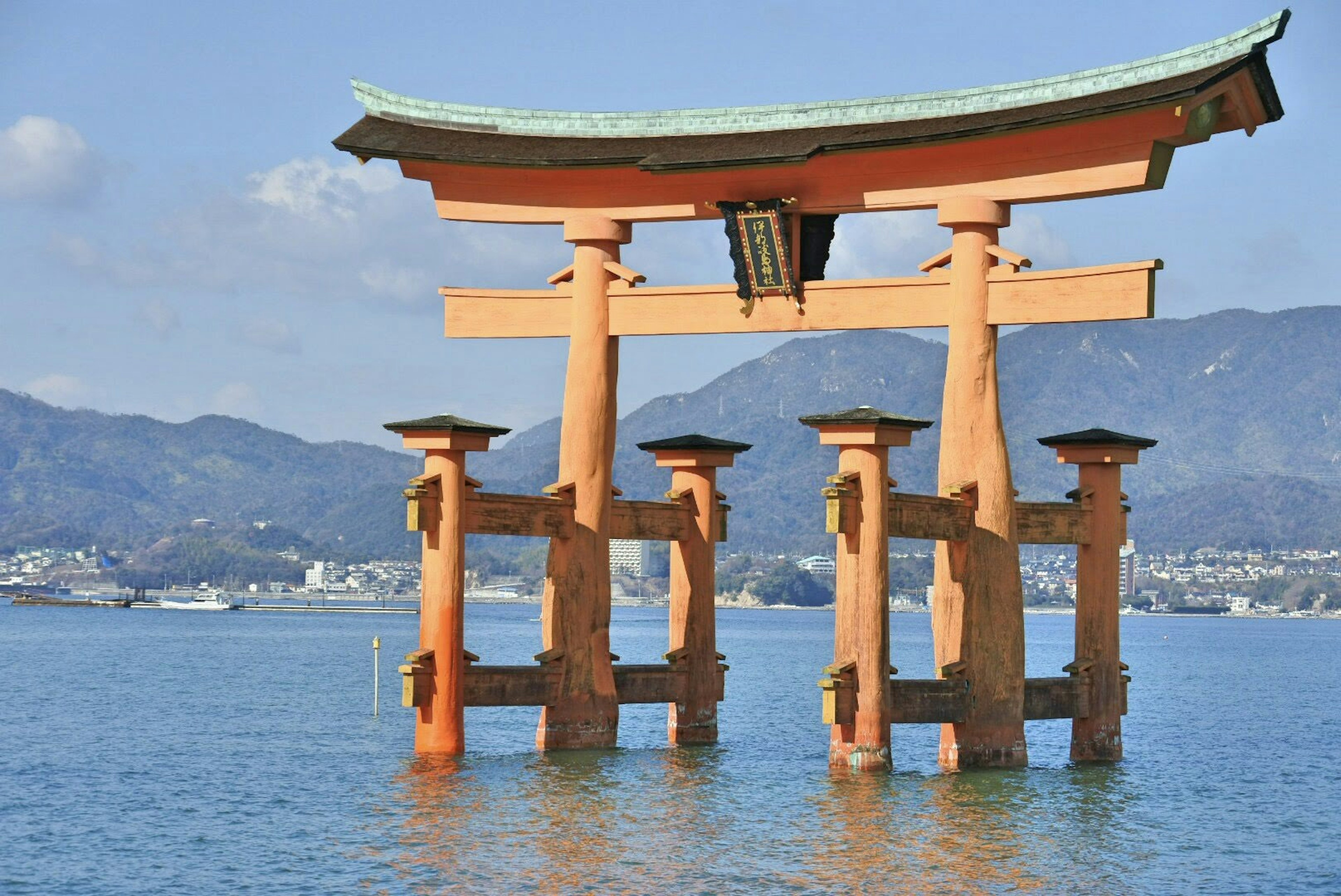 Una vista bellissima di un torii che si erge nell'acqua con montagne sullo sfondo