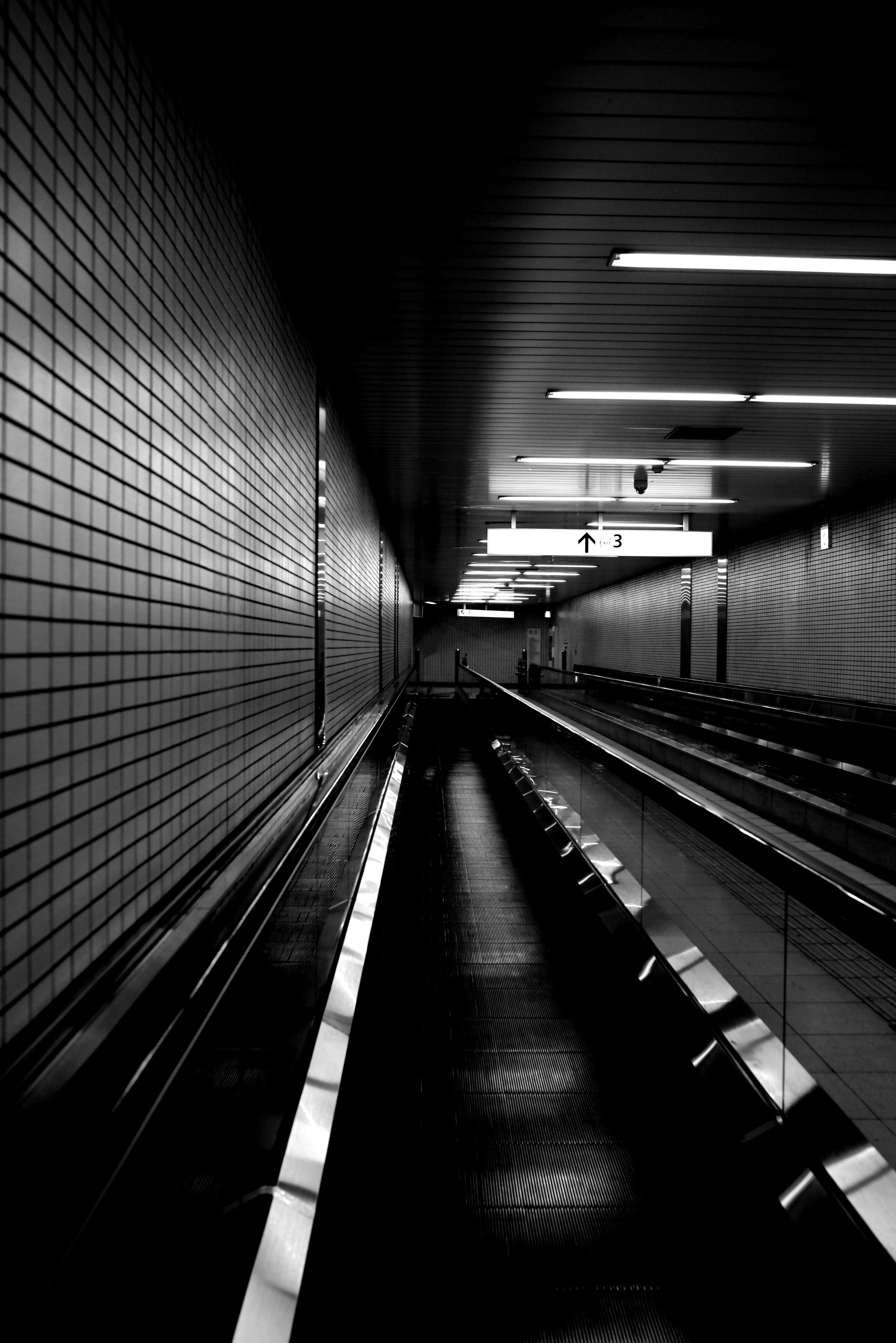 Long walkway in a dark tunnel with tiled walls