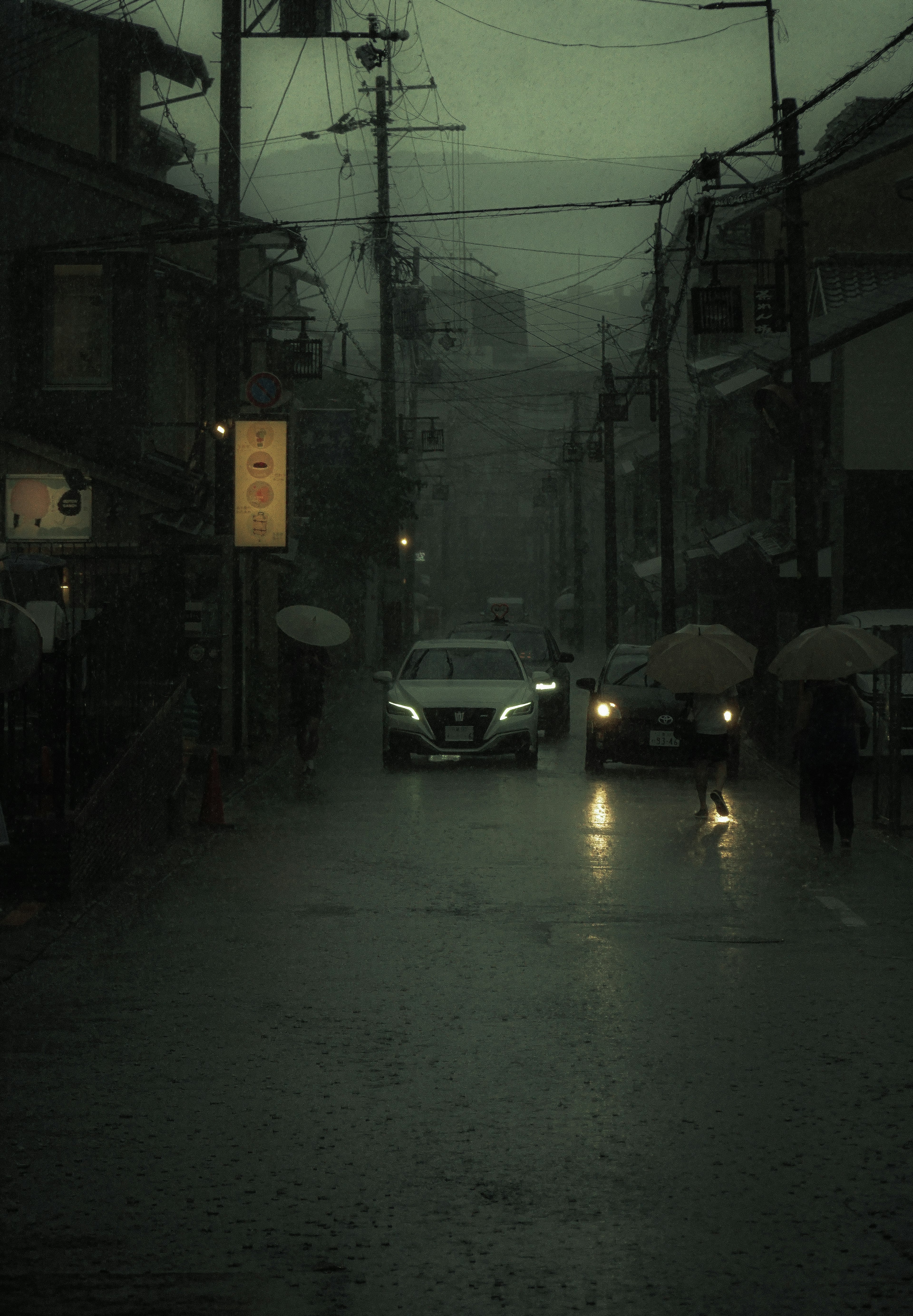 暗い雨の街並み 車と傘を持った人々