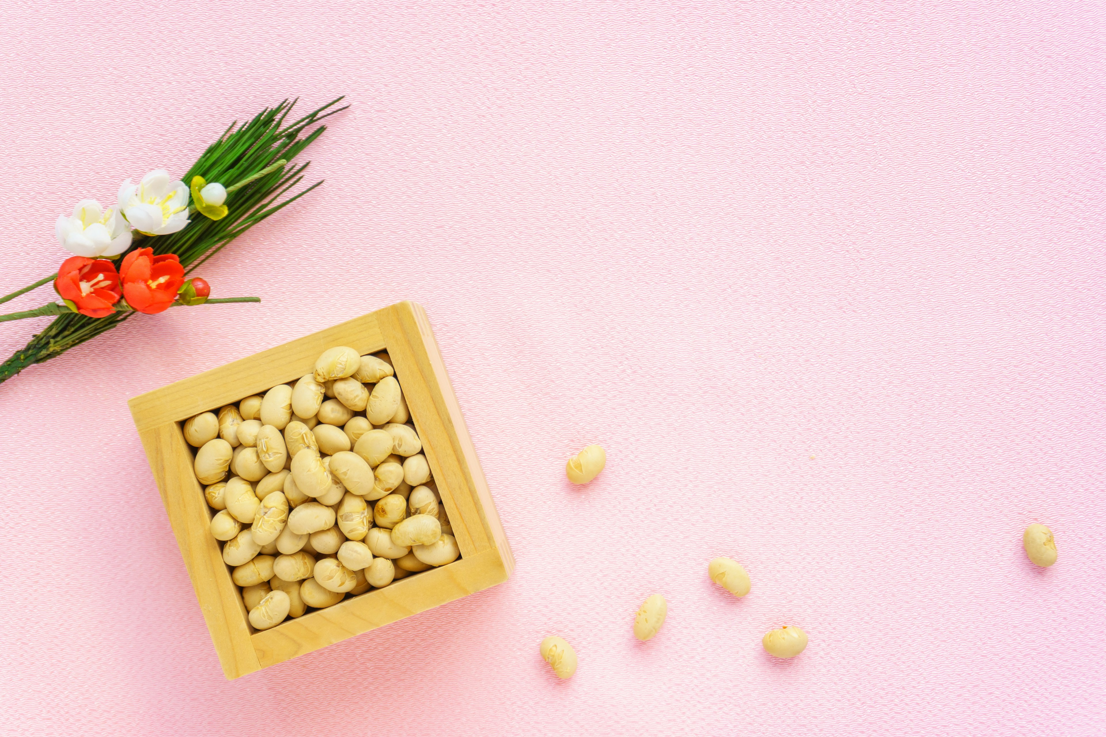 Mangkuk kayu penuh kacang di latar belakang merah muda dengan buket bunga kecil