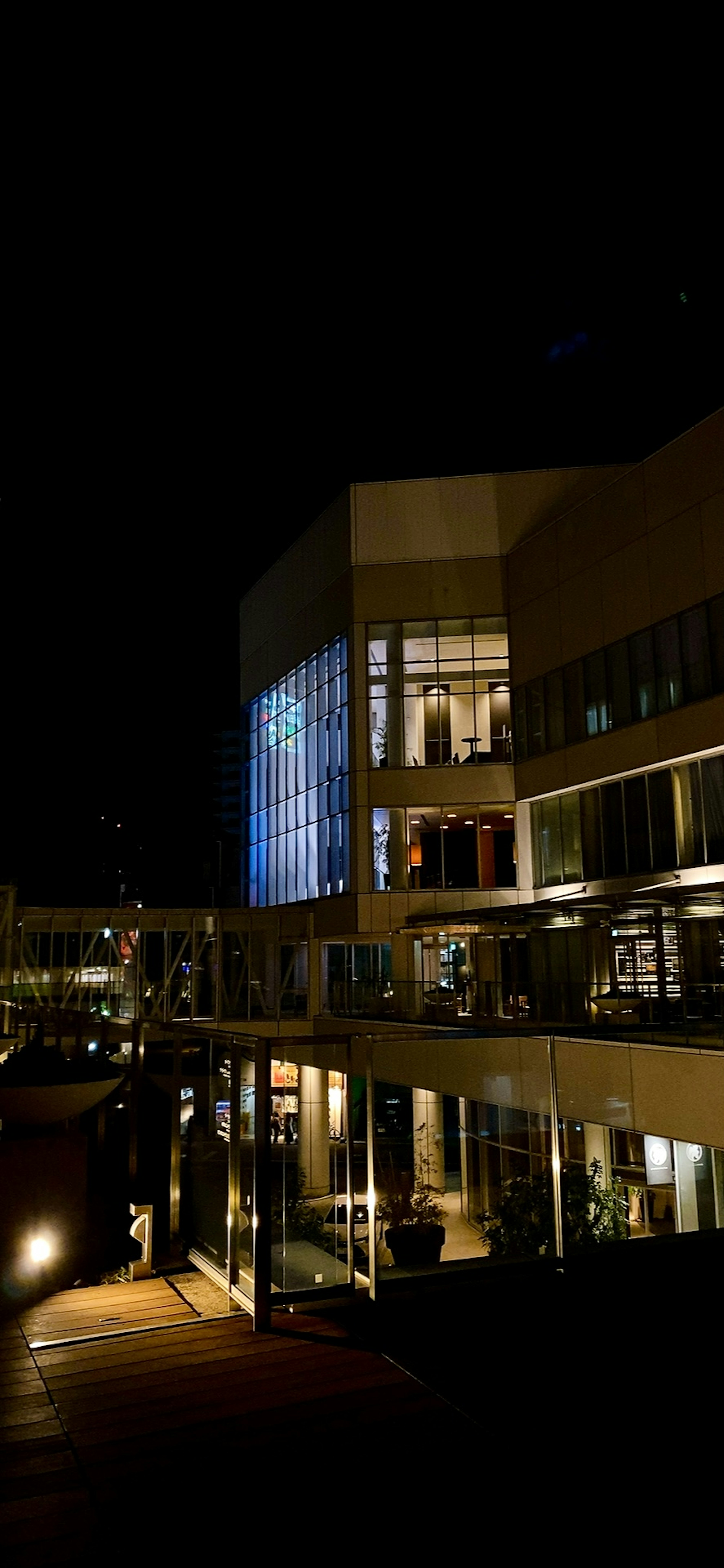 Vue nocturne d'un bâtiment et d'une terrasse avec un éclairage et des reflets magnifiques