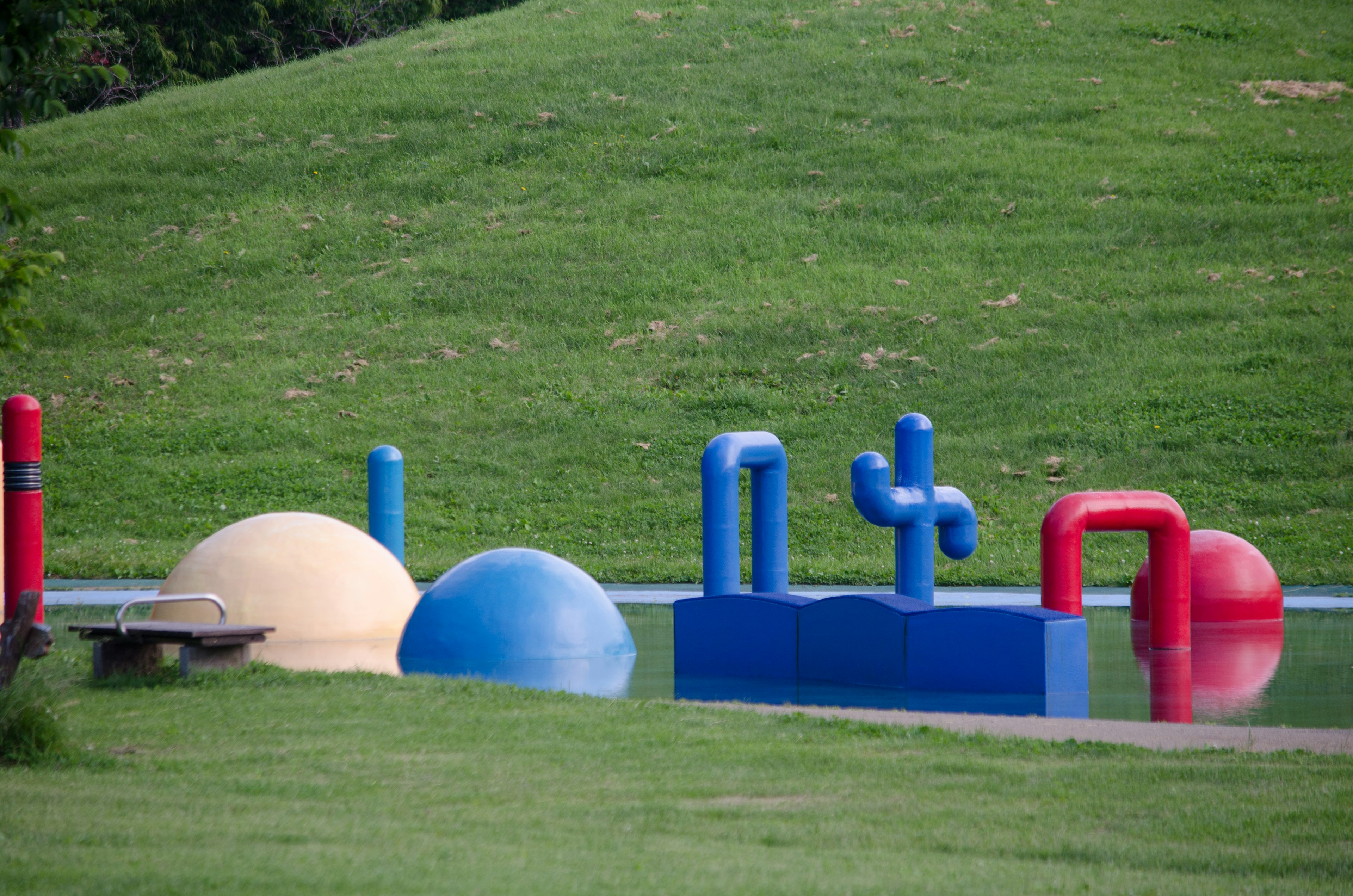 Colorful playground equipment in a park featuring red, blue, and yellow shapes