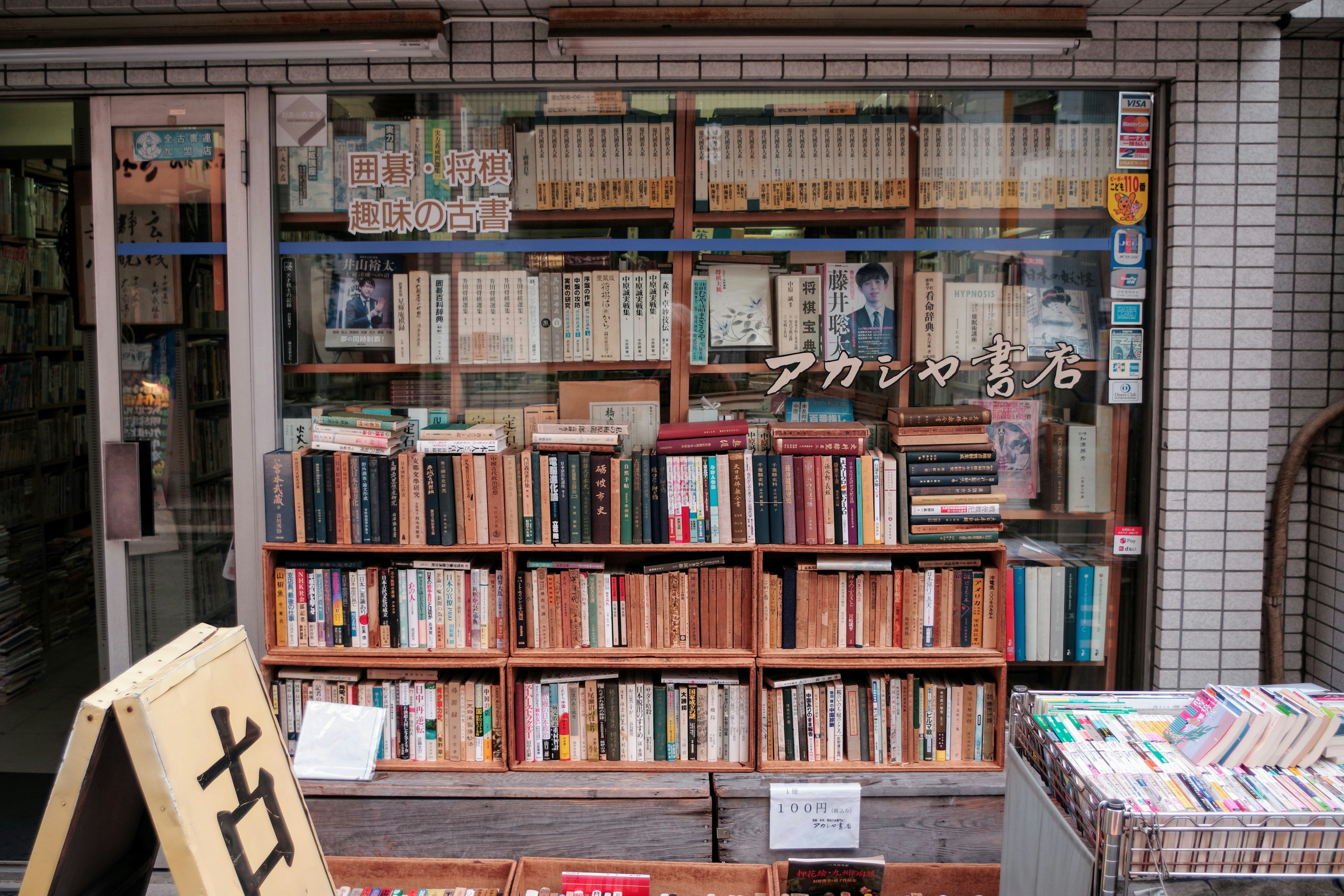 Bookshelves filled with various books in a secondhand bookstore window