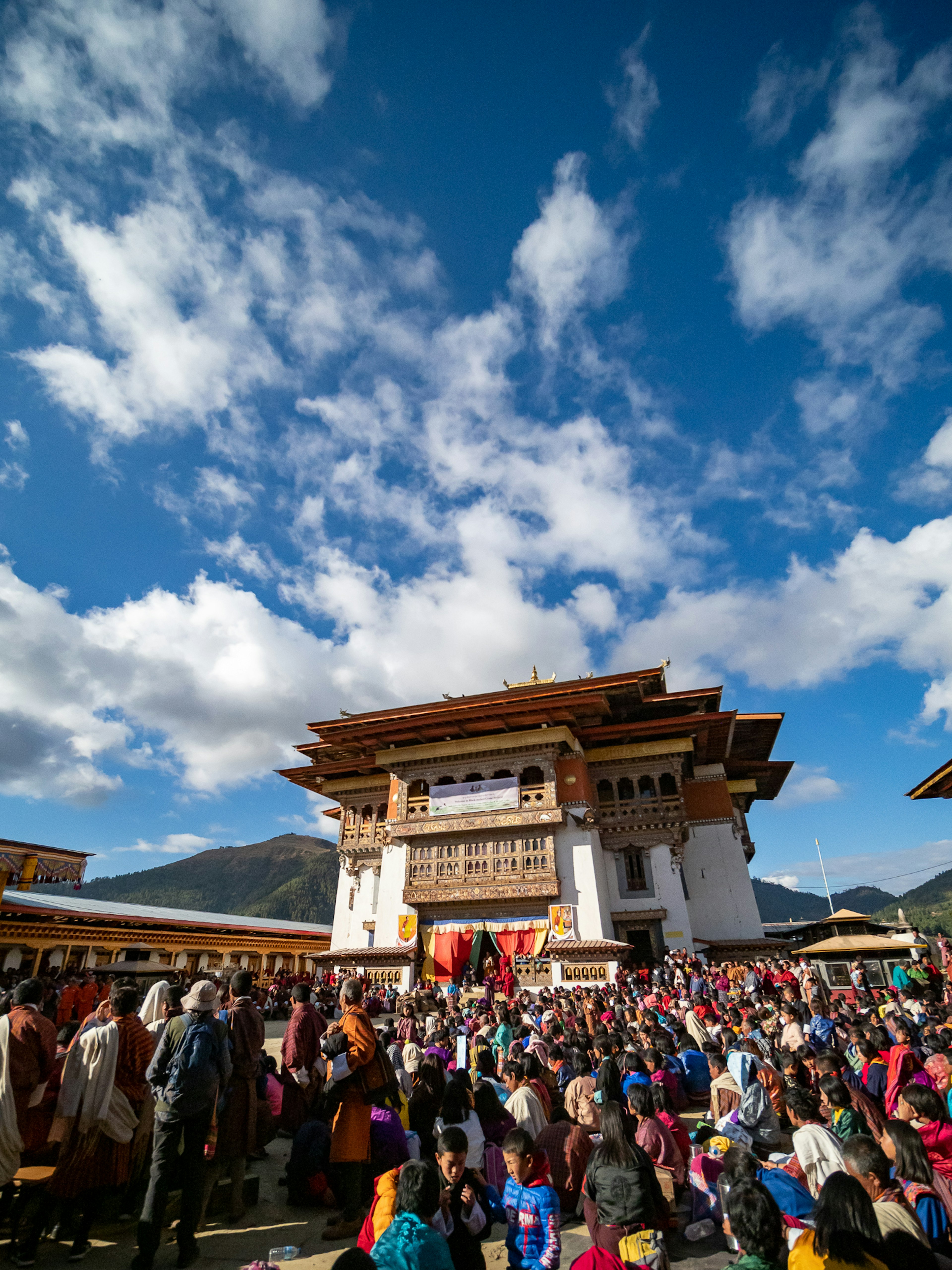 人群聚集在傳統建築前，美麗藍天白雲下的場景