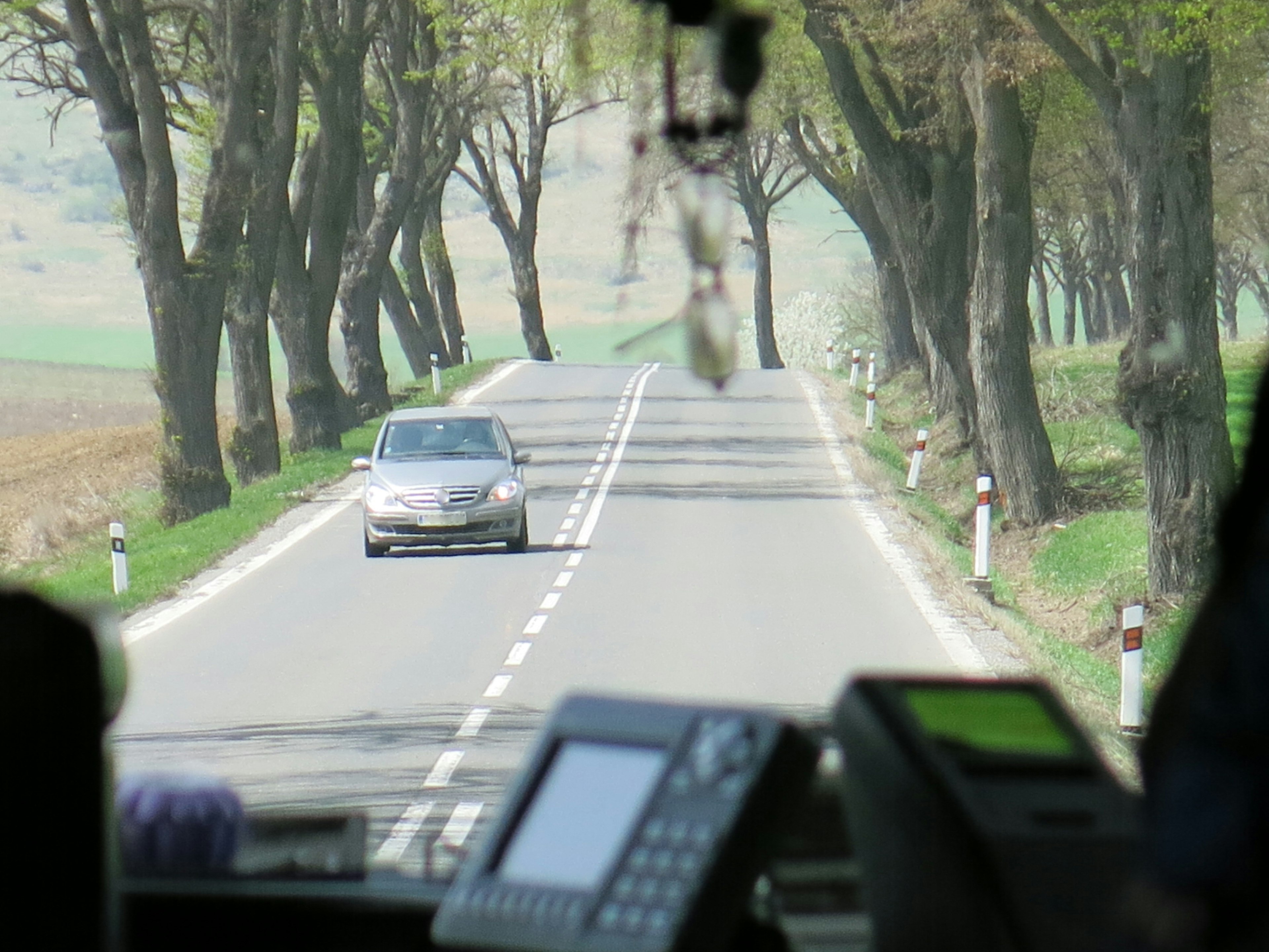 Un coche conduciendo por una carretera rural rodeada de árboles verdes