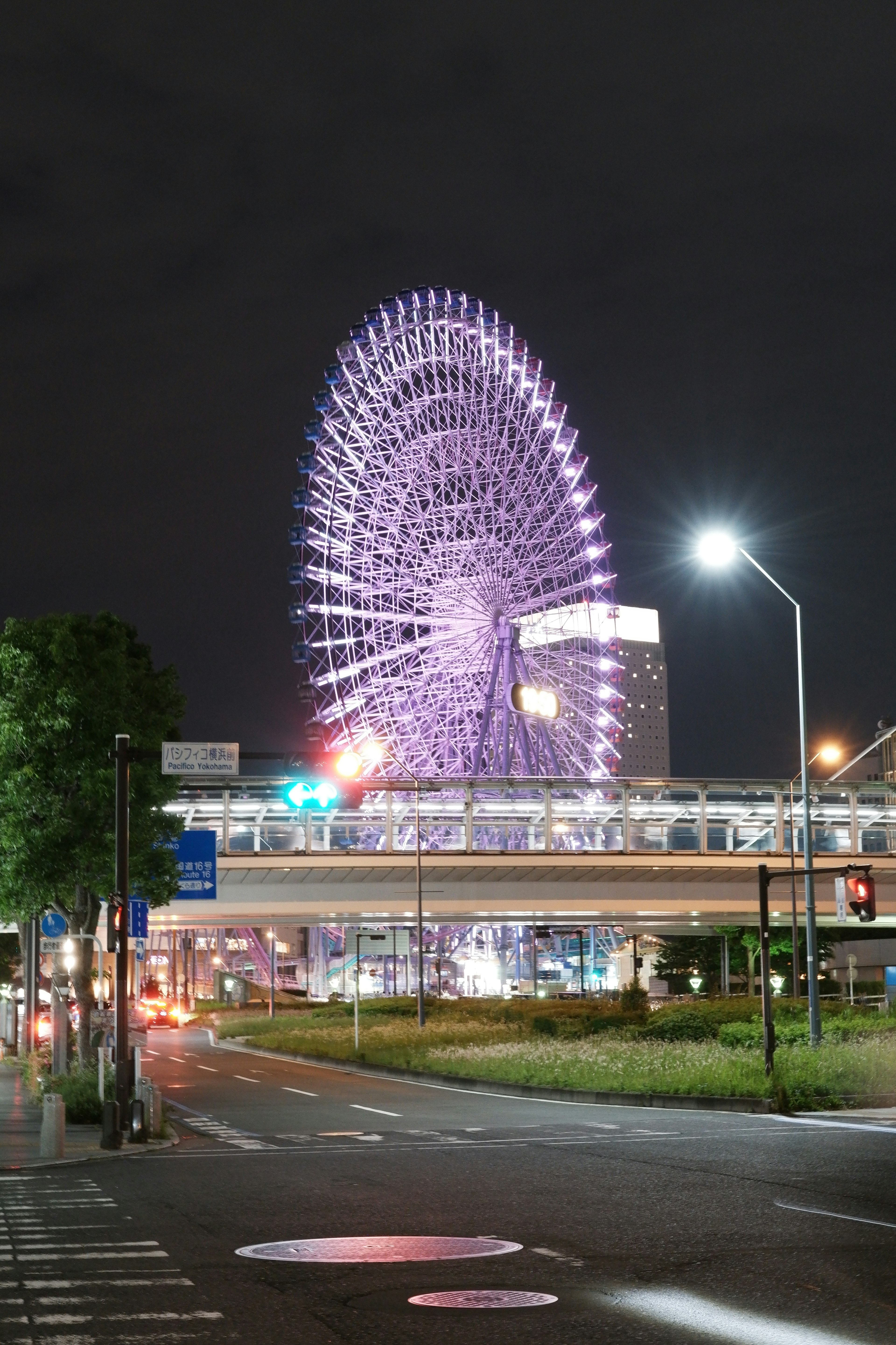 Pemandangan kota dengan roda ferris ungu yang menyala di malam hari