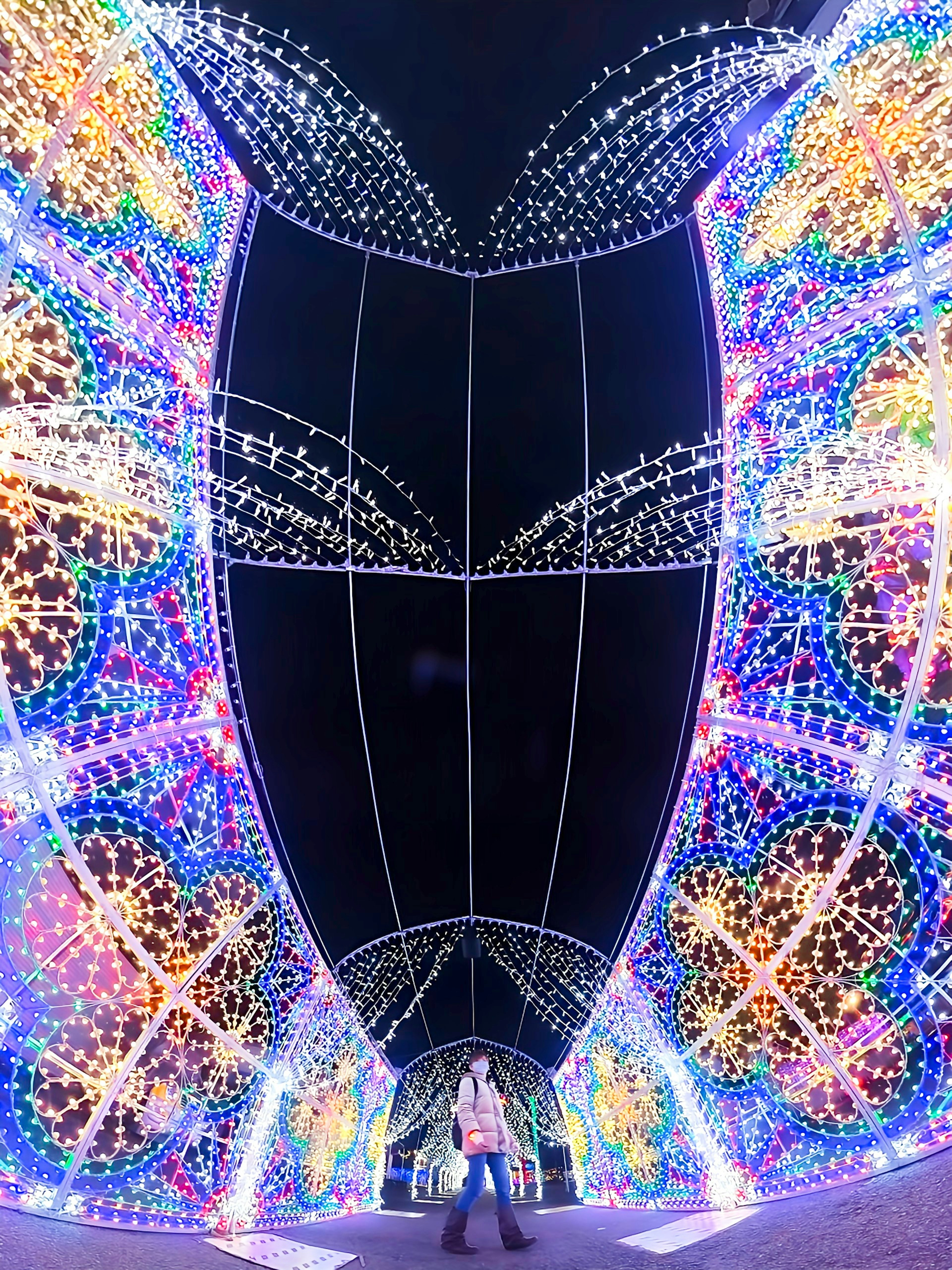 A person standing in a colorful light tunnel at night