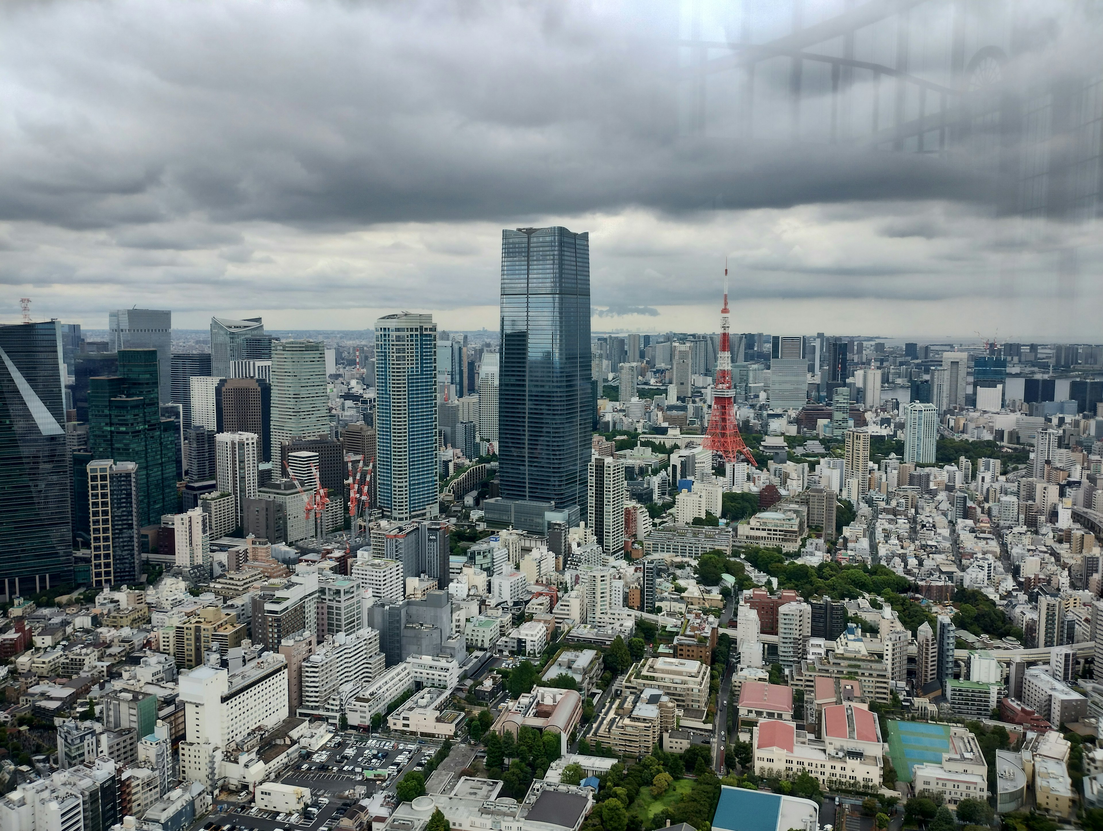 Pemandangan garis langit Tokyo dengan gedung pencakar langit dan Menara Tokyo di bawah langit berawan