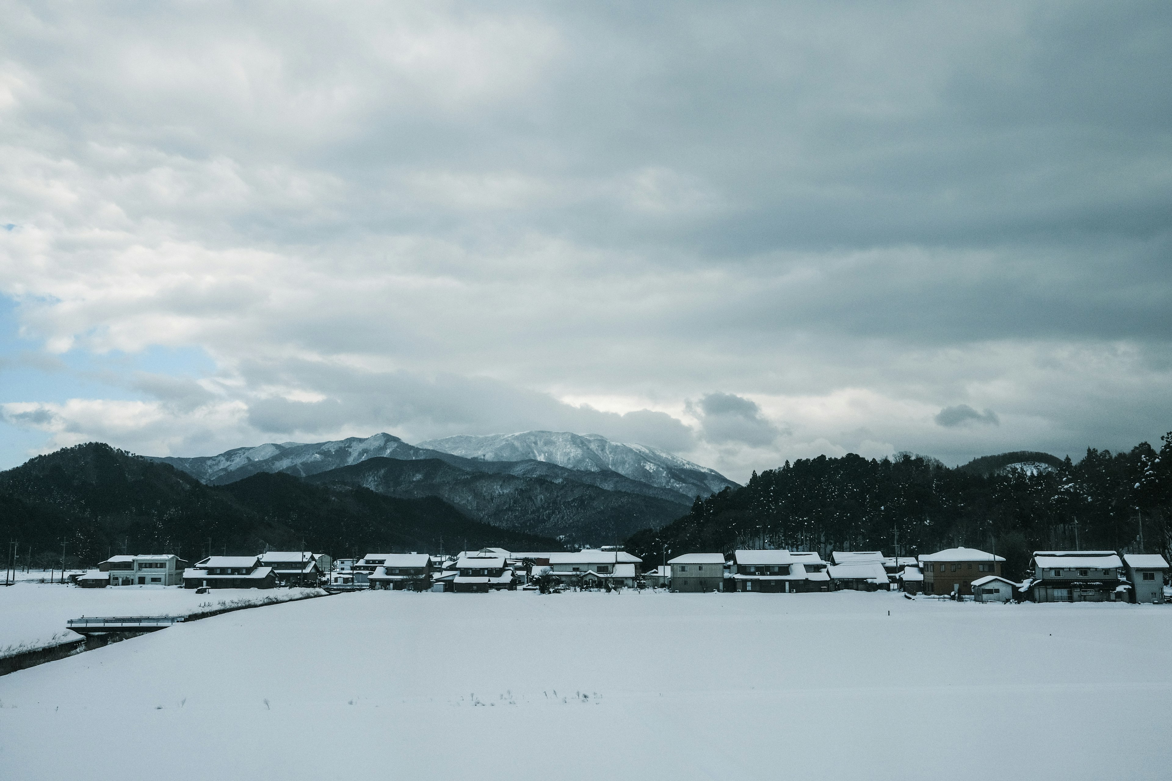 Snow-covered rural landscape with mountains in the background