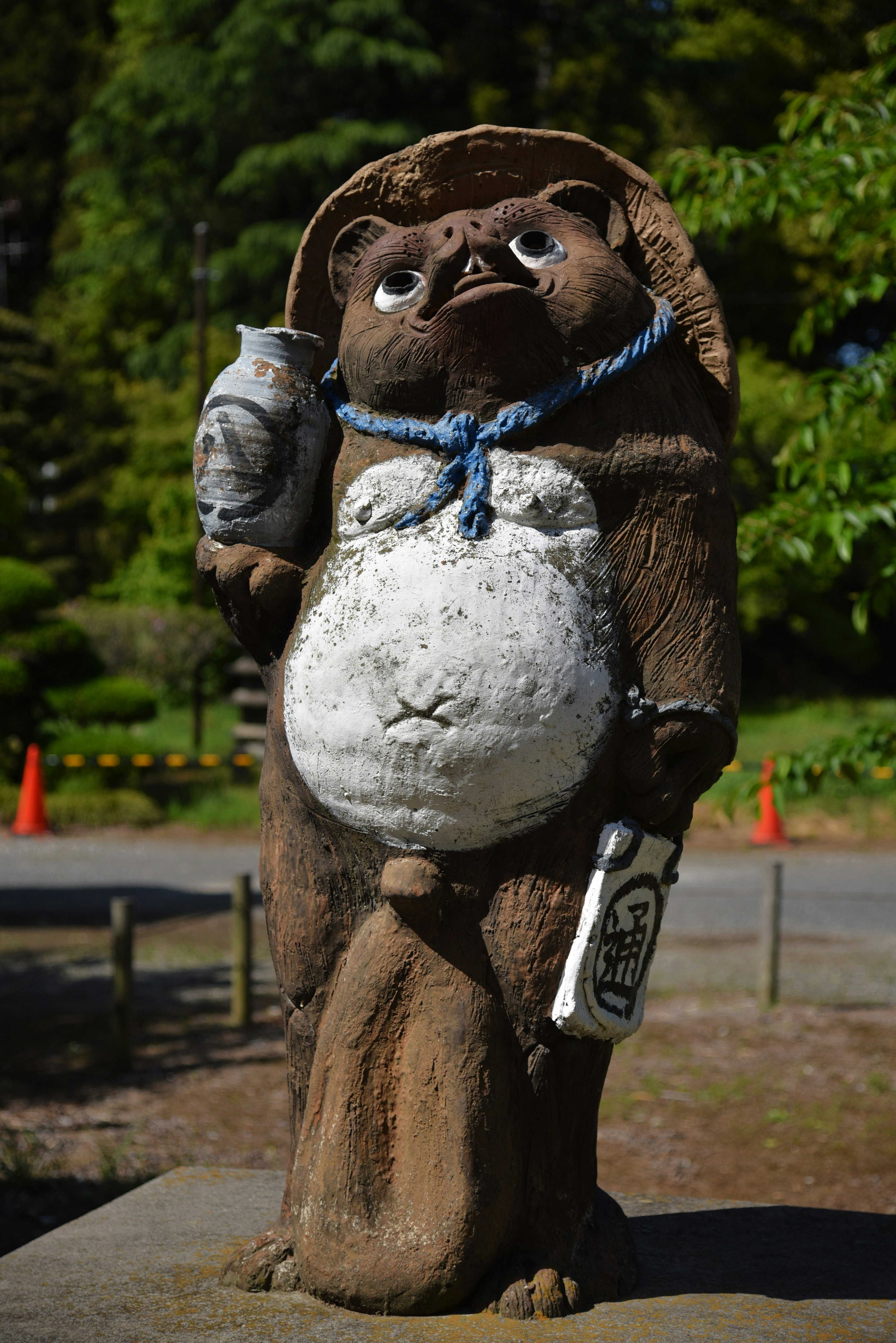 Una statua di tanuki che tiene una bottiglia e un uccello