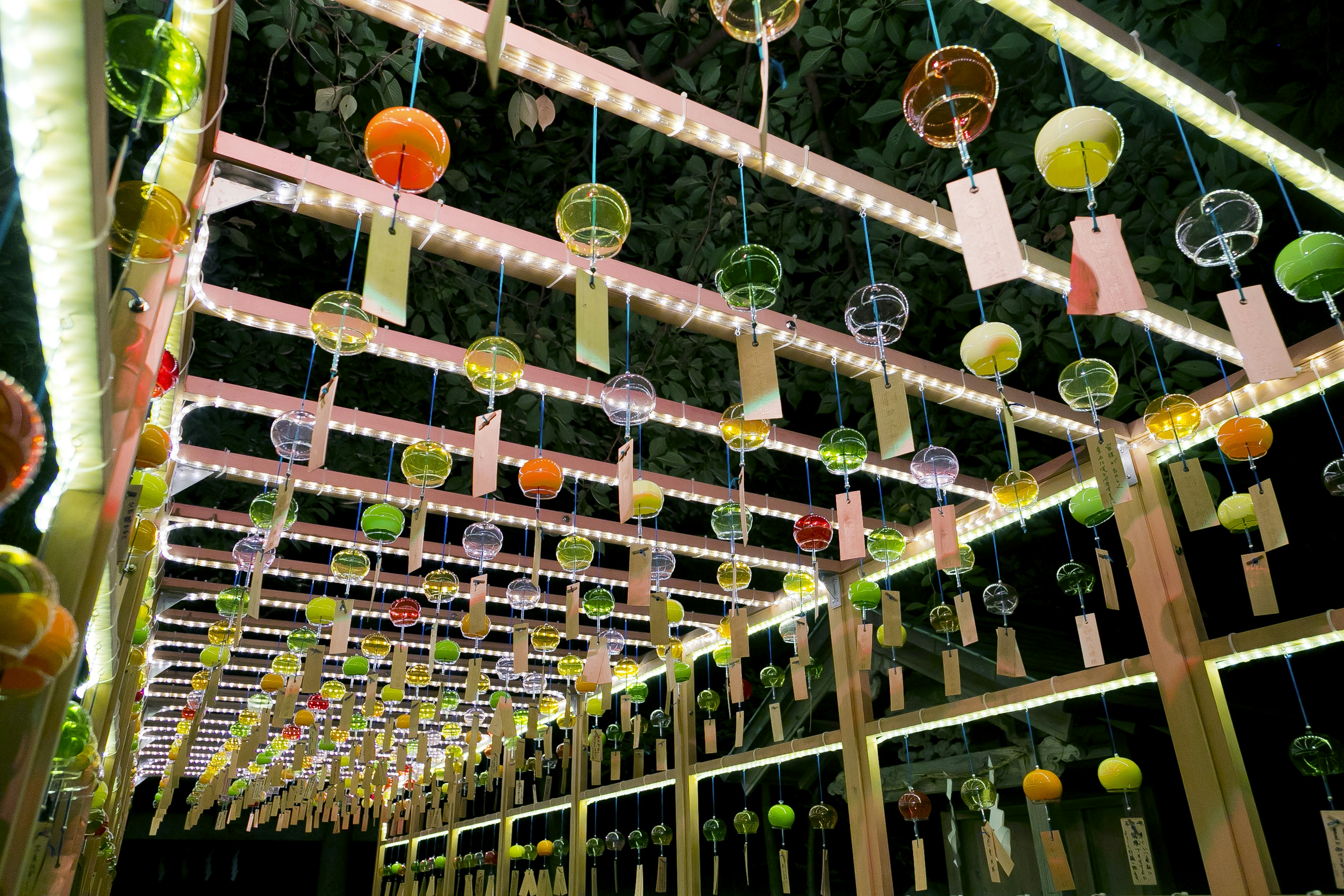 Colorful wind chimes arching under soft lights at night