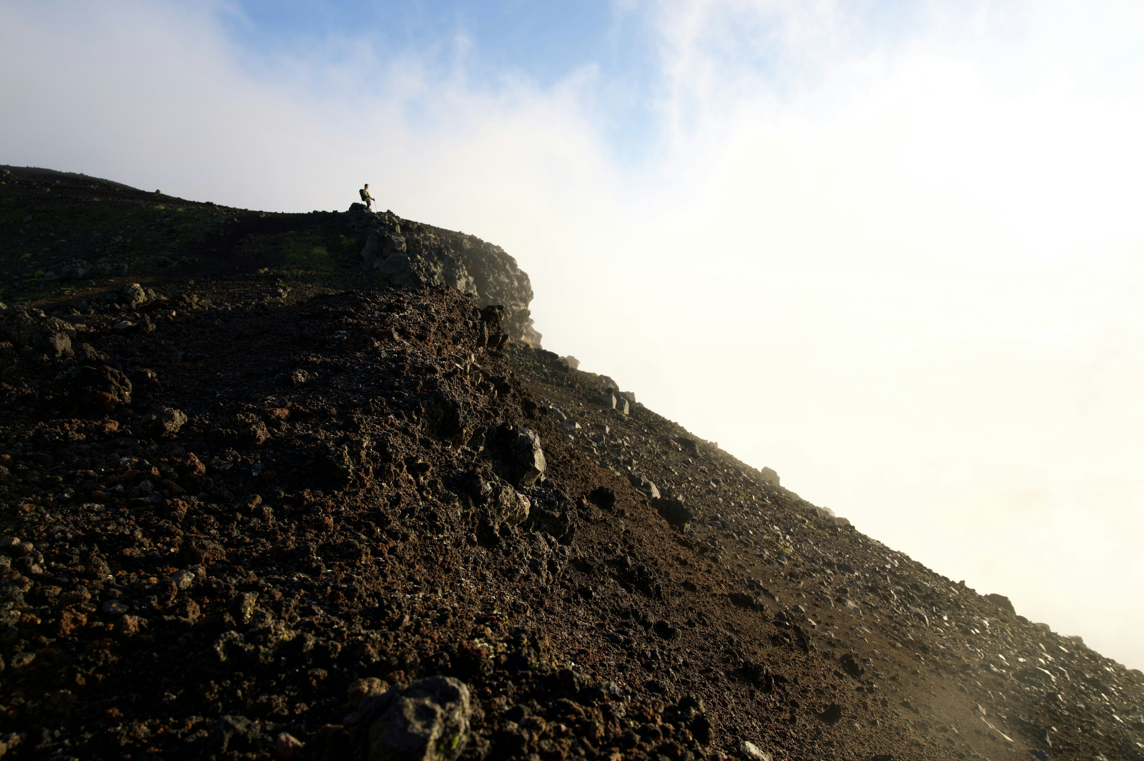 Wanderer auf einem steinigen Berghang umgeben von Nebel