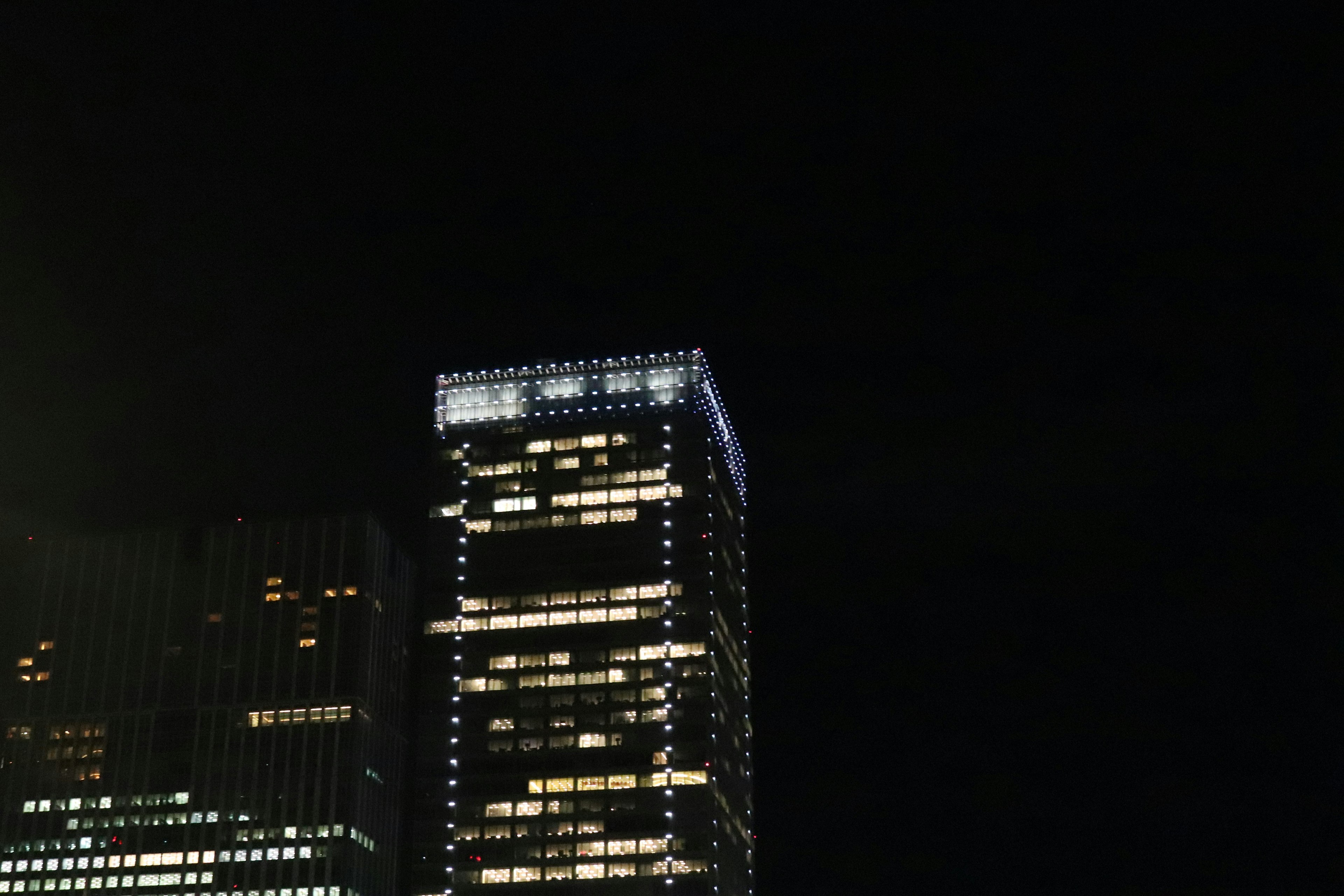 Beleuchteter Wolkenkratzer bei Nacht mit dunklem Hintergrund