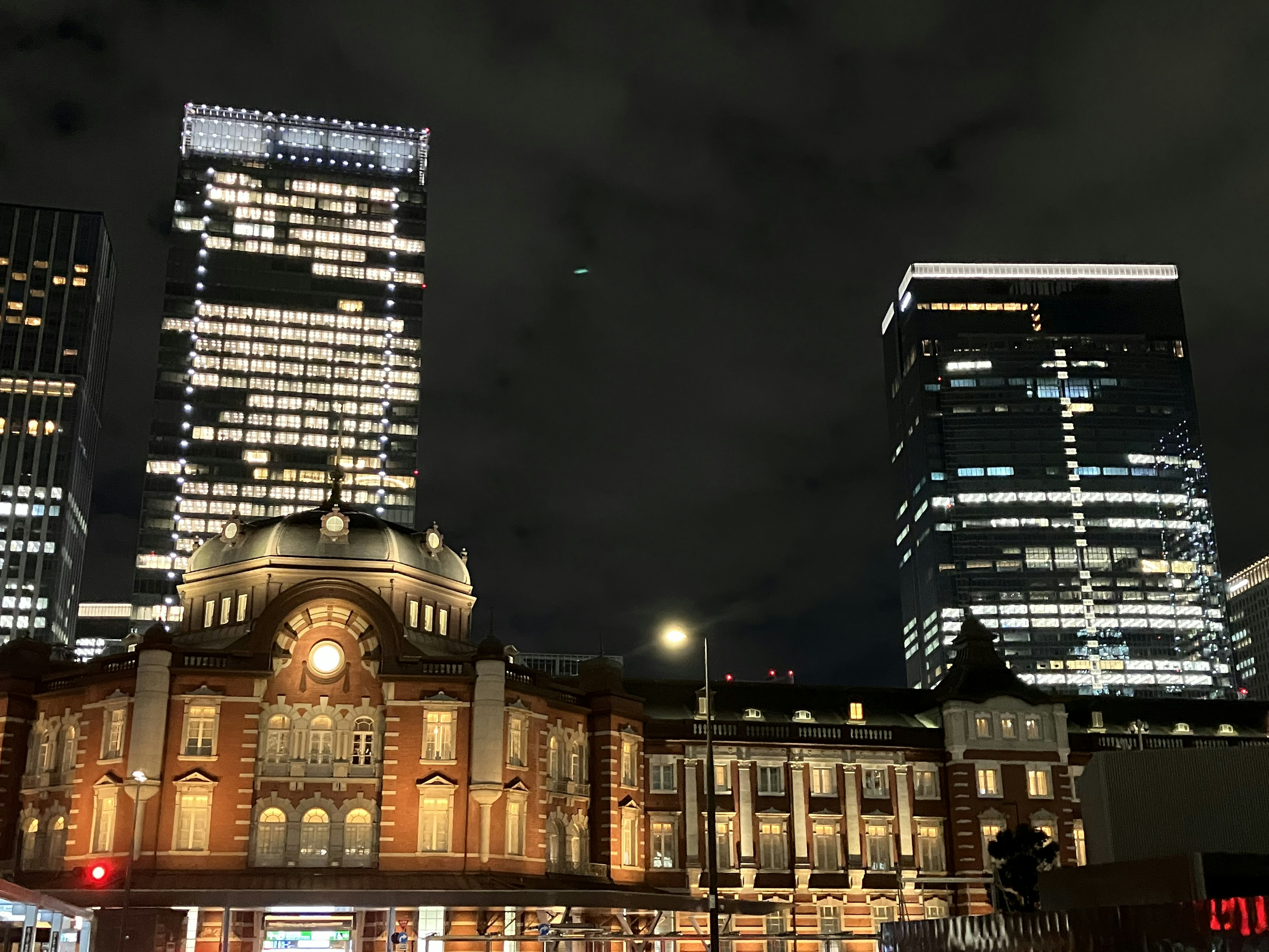 Estación de Tokio iluminada por la noche con rascacielos modernos