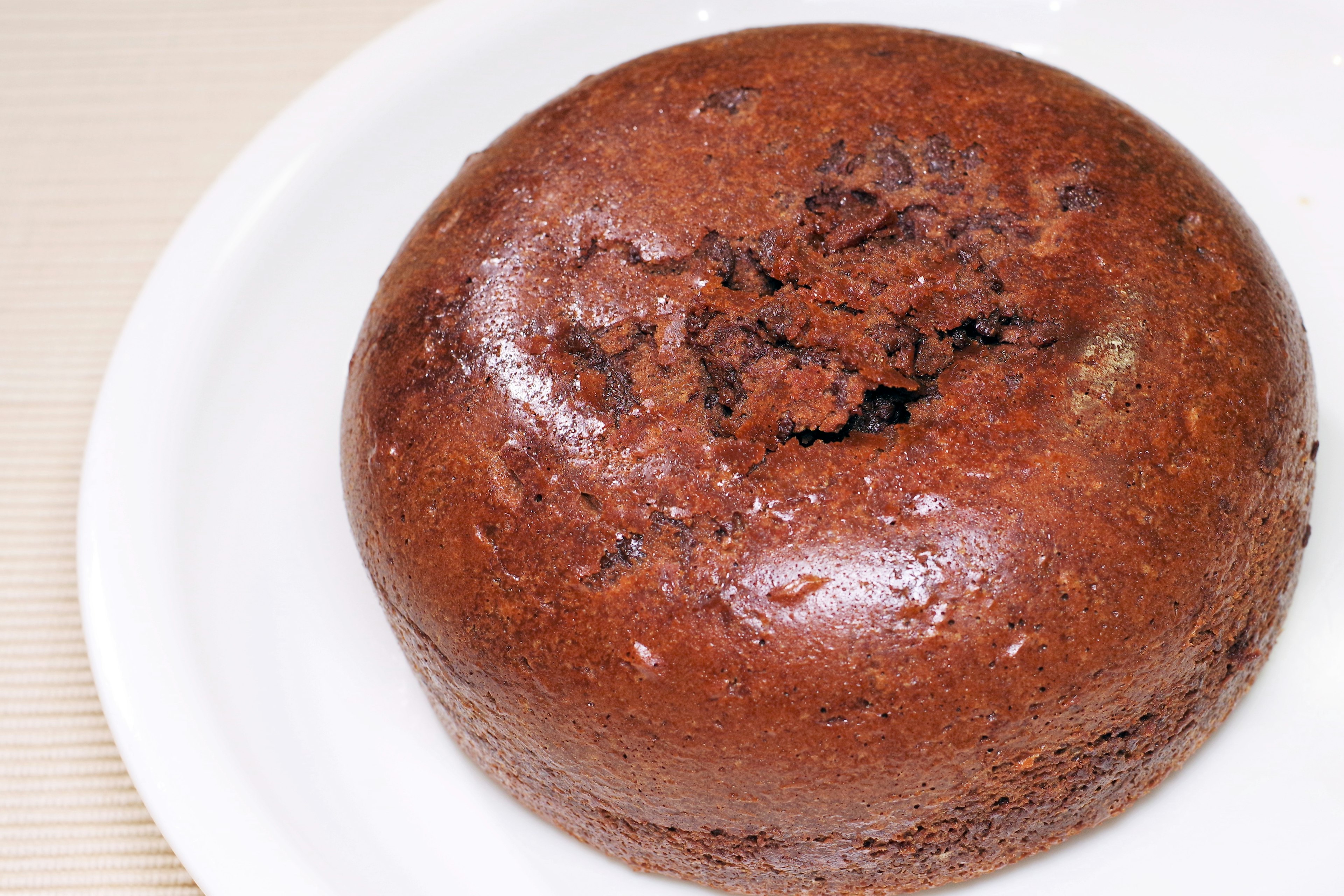 Schokoladenkuchen mit einem Loch oben auf einem weißen Teller serviert