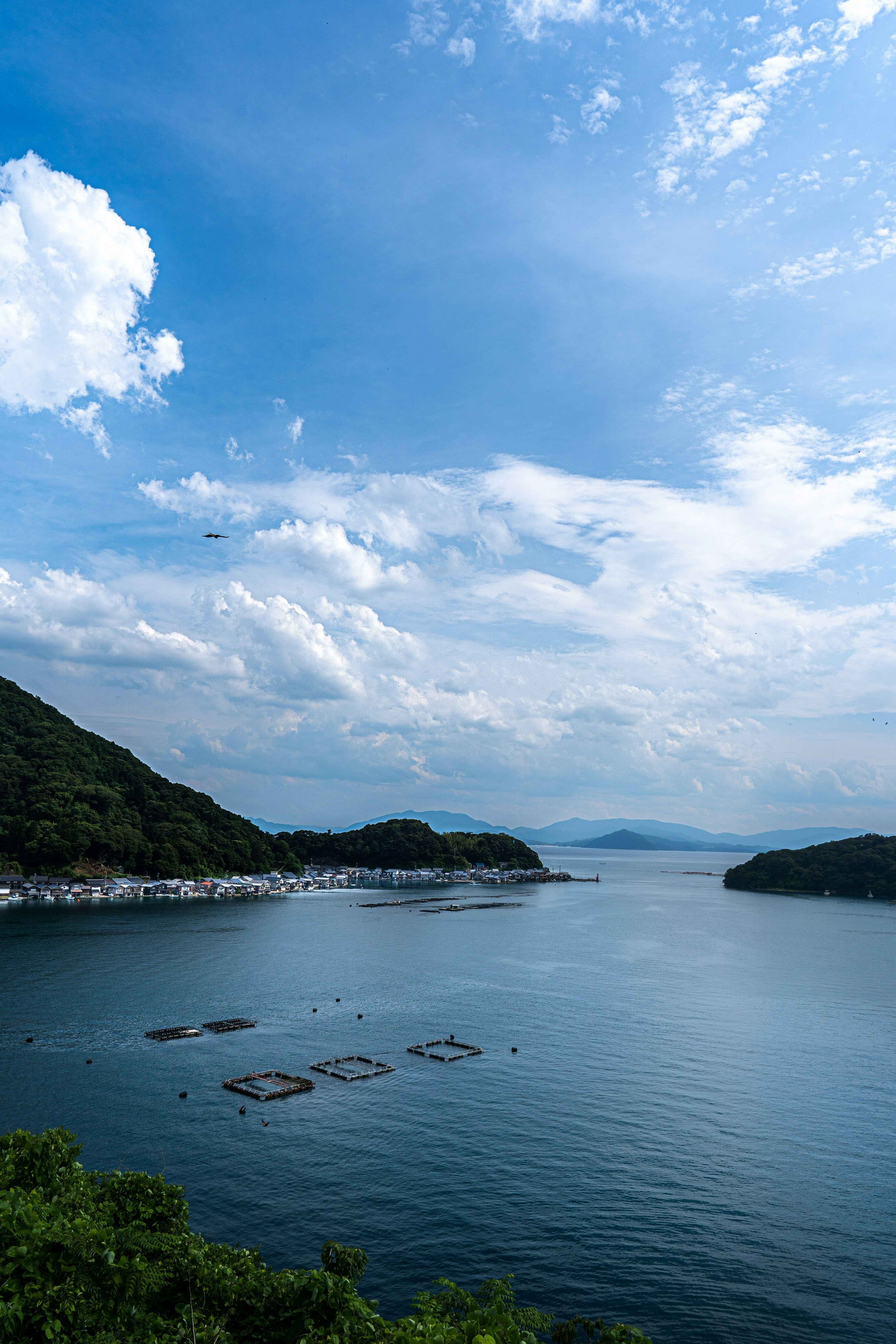 廣闊的藍色海洋，散布的雲朵和遙遠的山丘