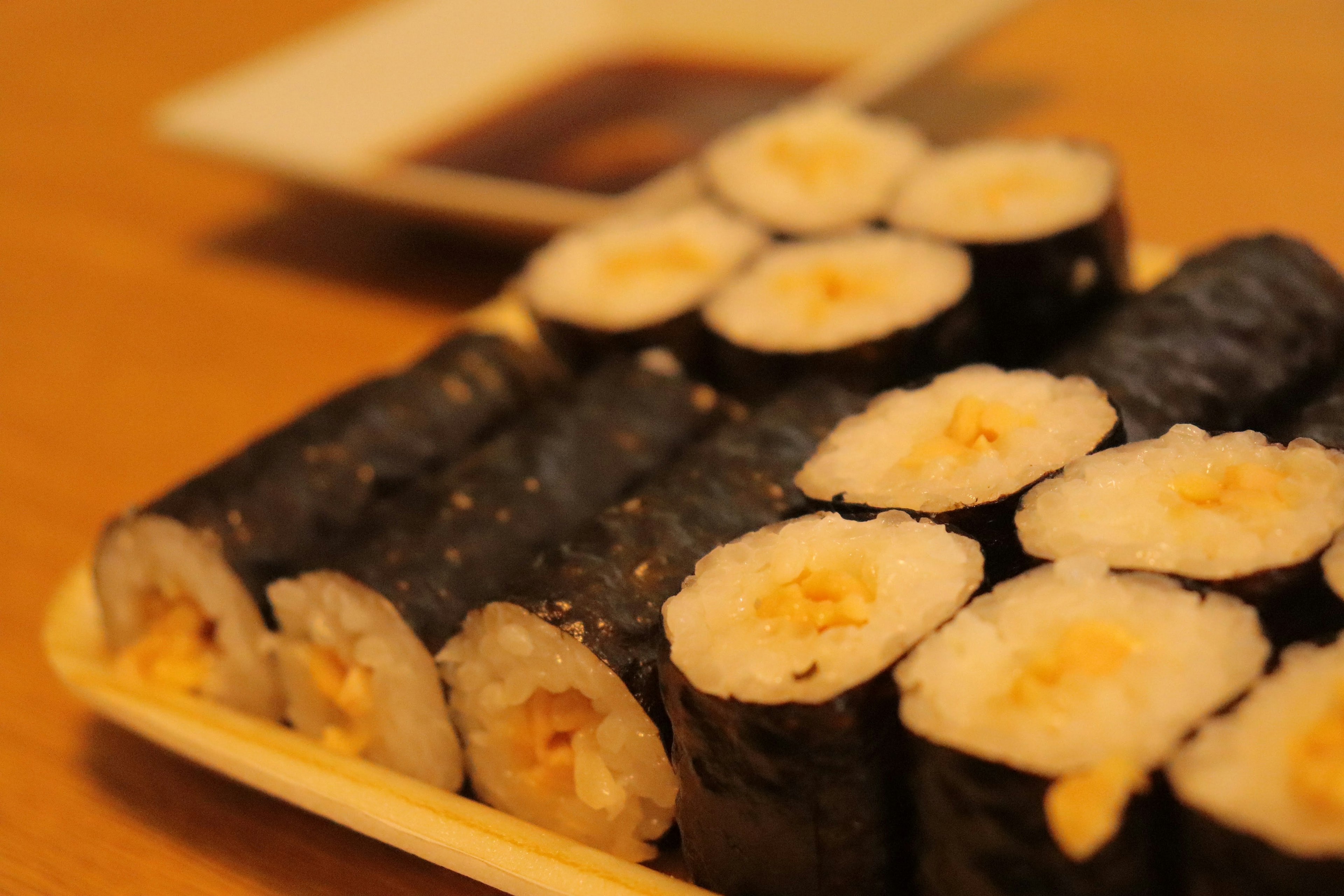 Piring sushi gulung dengan nori dan piring kecap