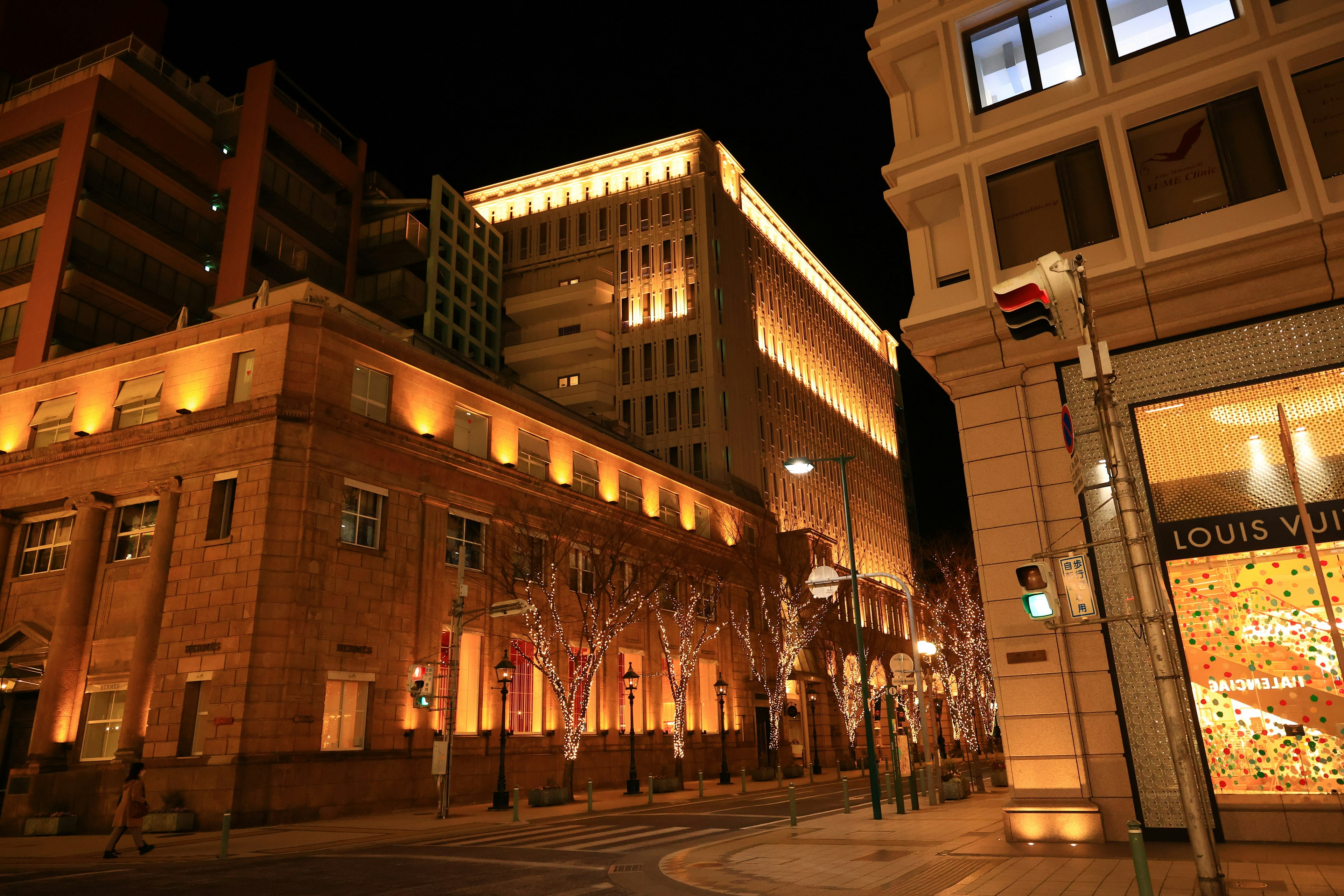 Illuminated cityscape at night featuring buildings and white trees