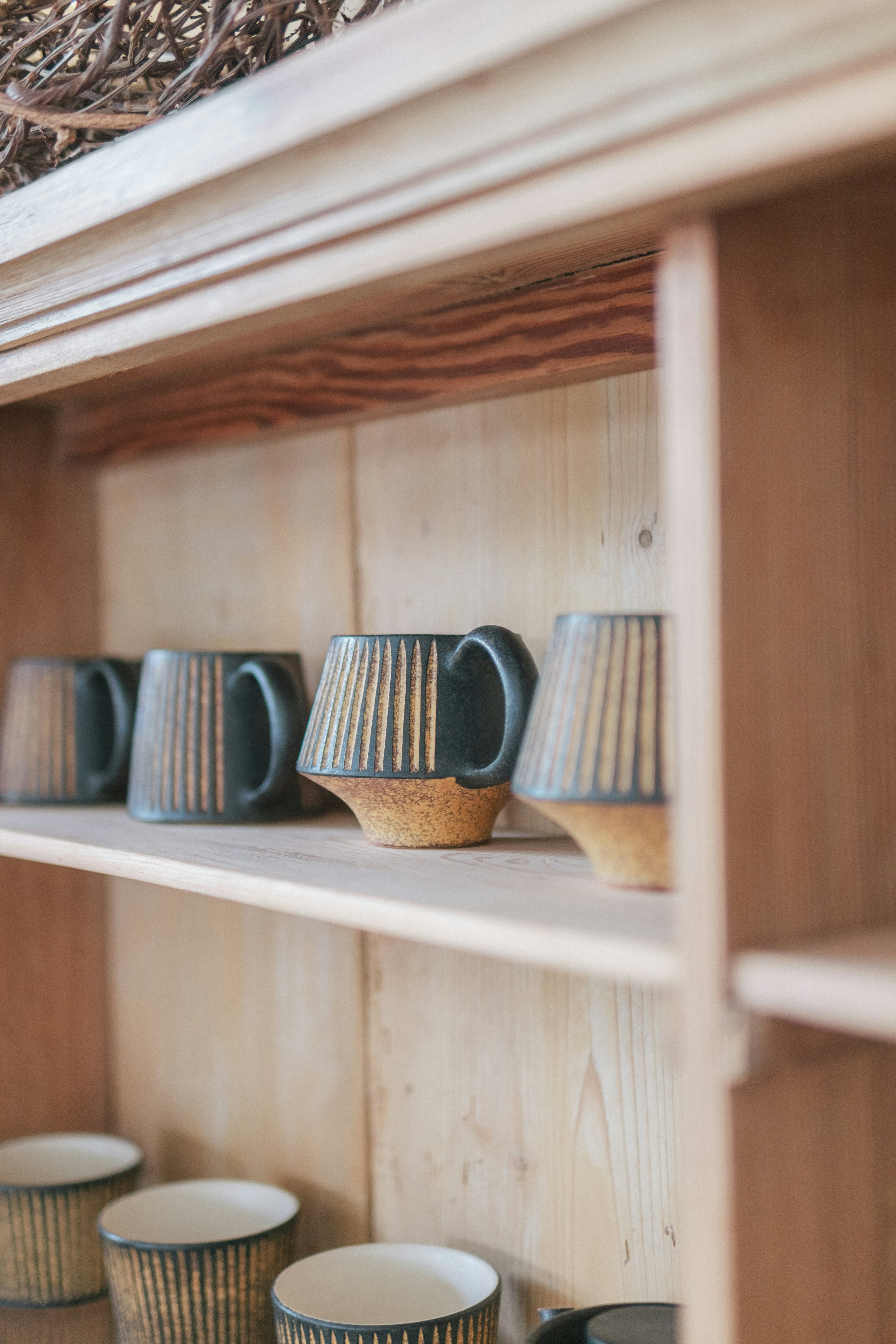 Beaux mugs en céramique disposés sur une étagère en bois