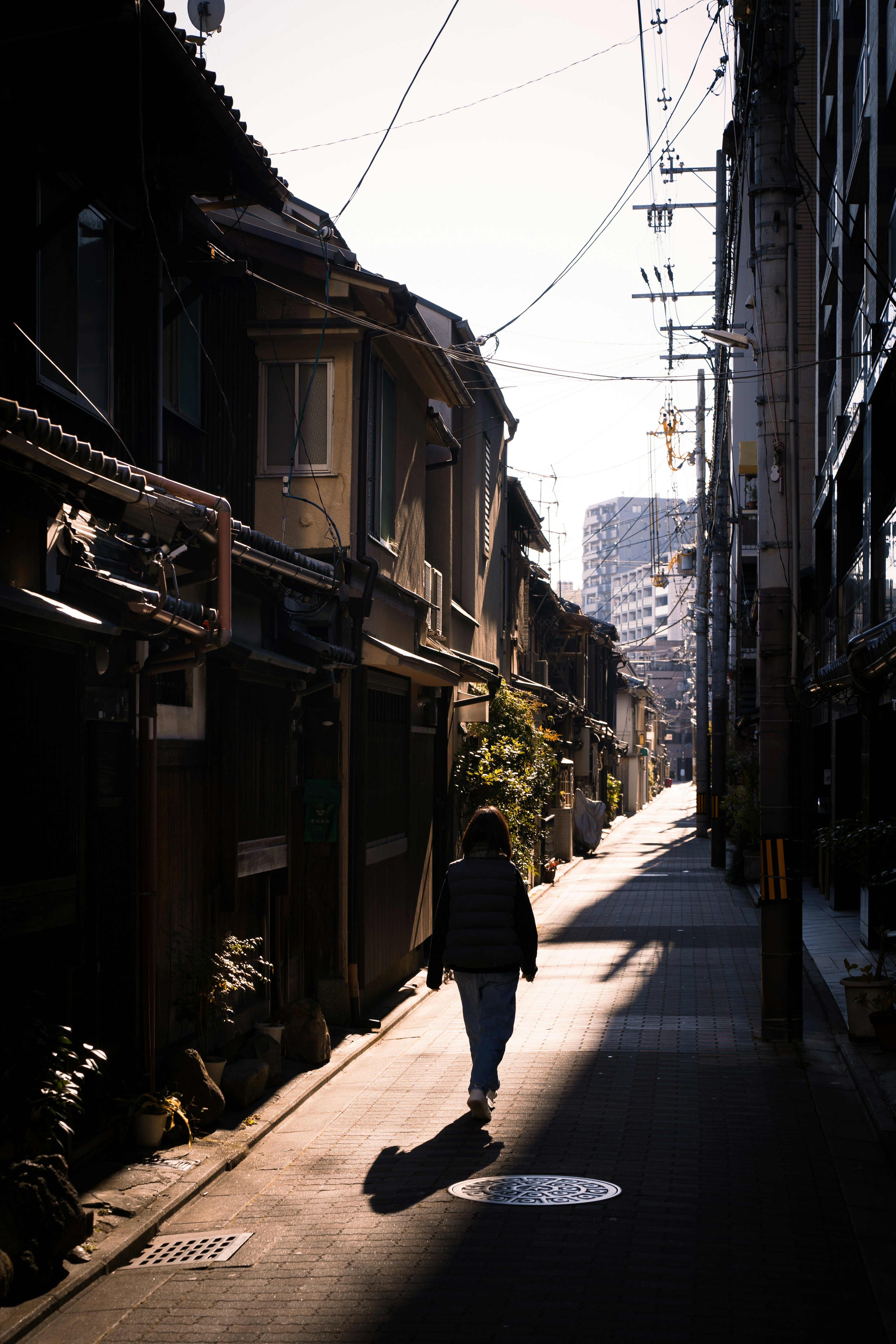 Silhouette d'une personne marchant dans une ruelle faiblement éclairée avec des bâtiments calmes