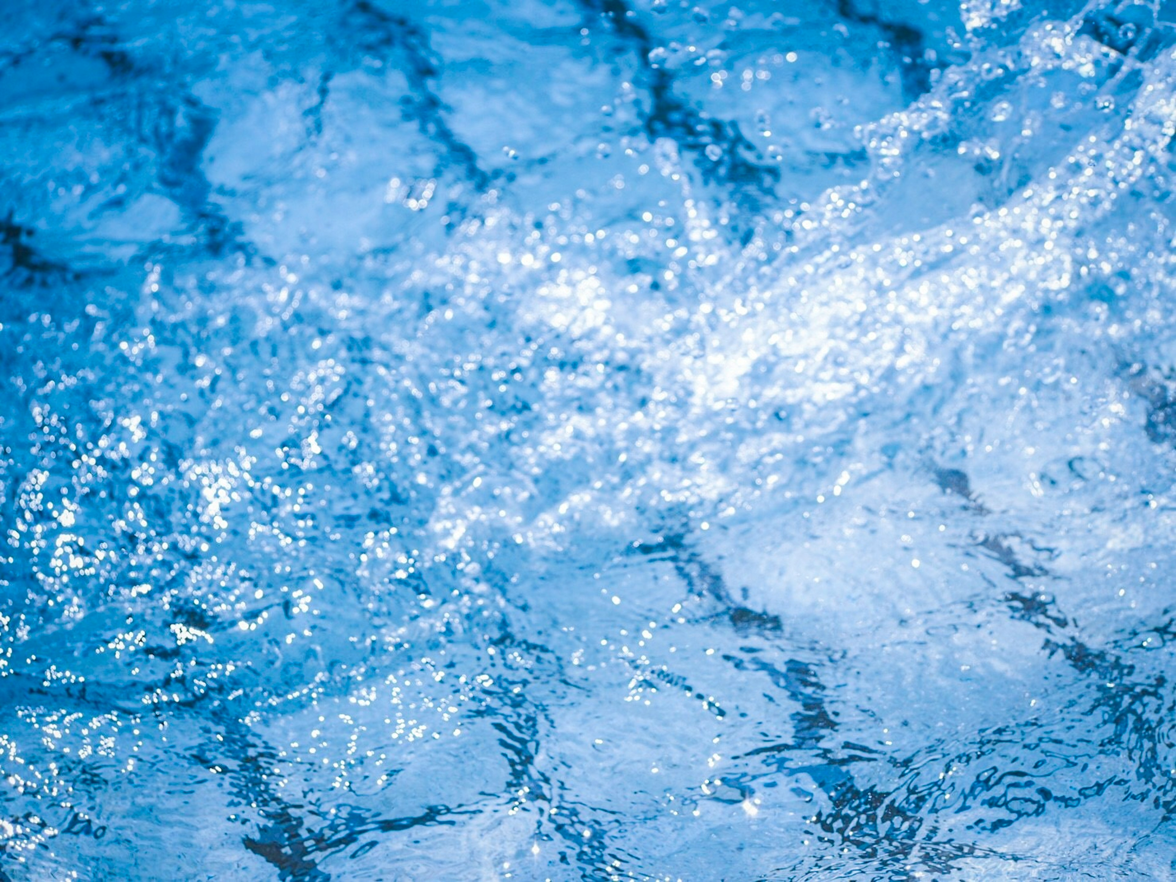 Superficie de agua azul ondulante con reflejos de luz