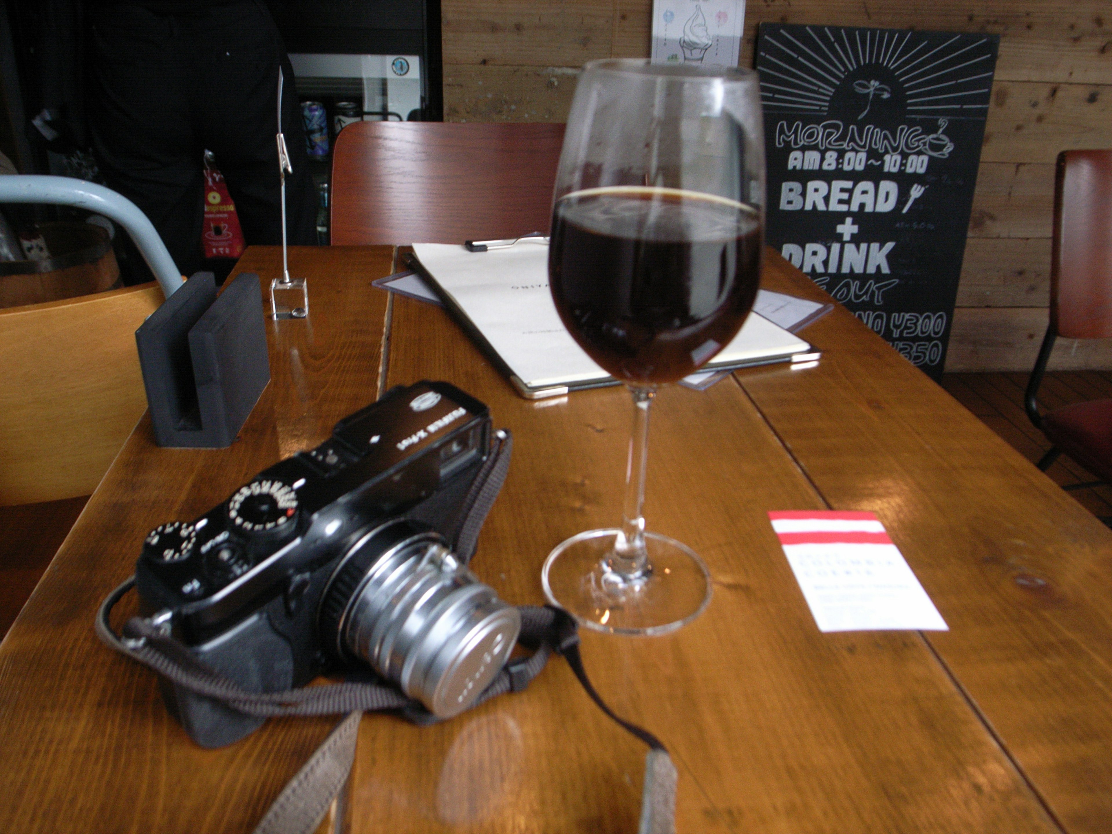 A camera and a glass of red wine on a wooden table