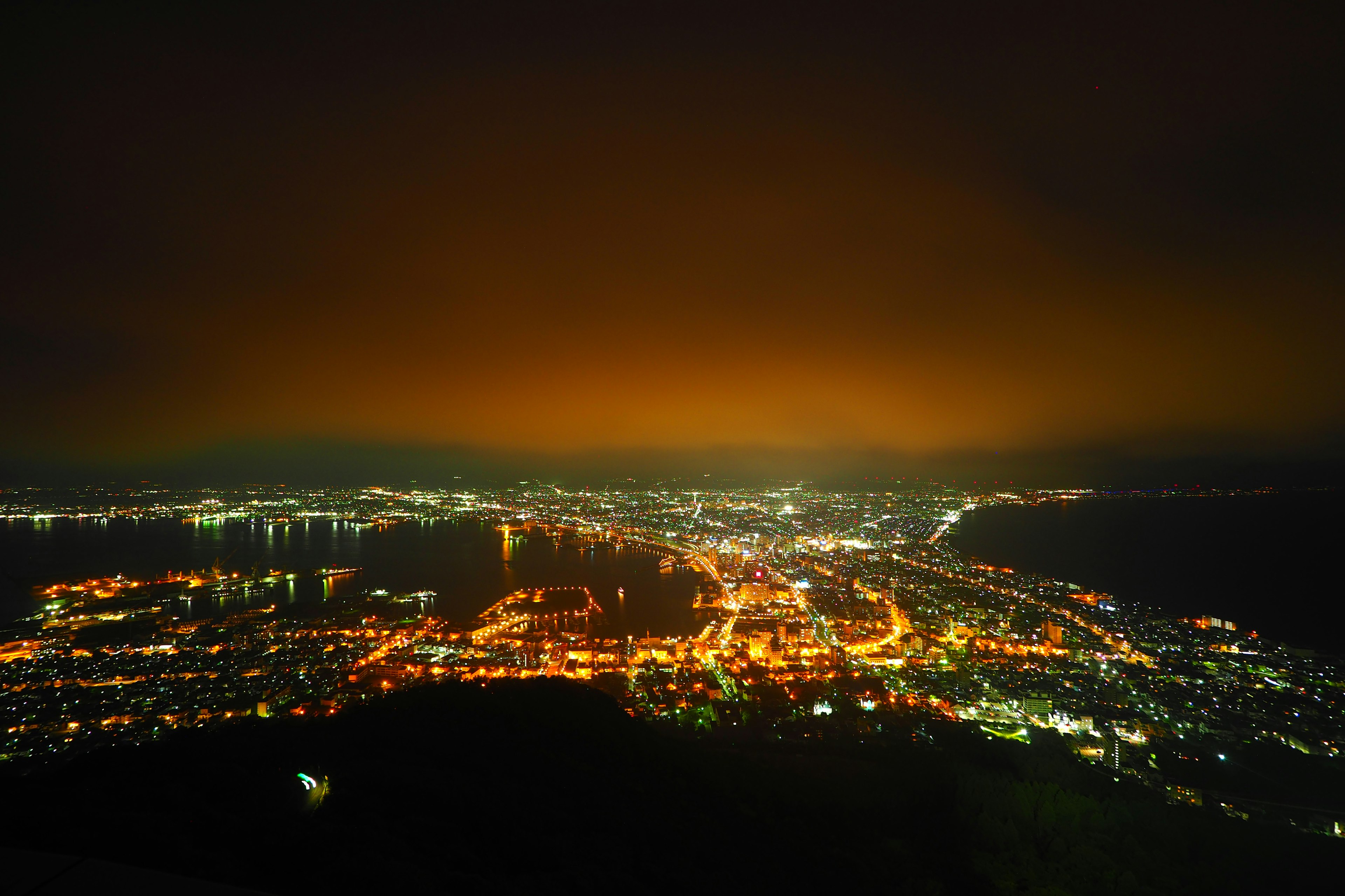 Panoramic view of a beautiful city at night illuminated by orange sky