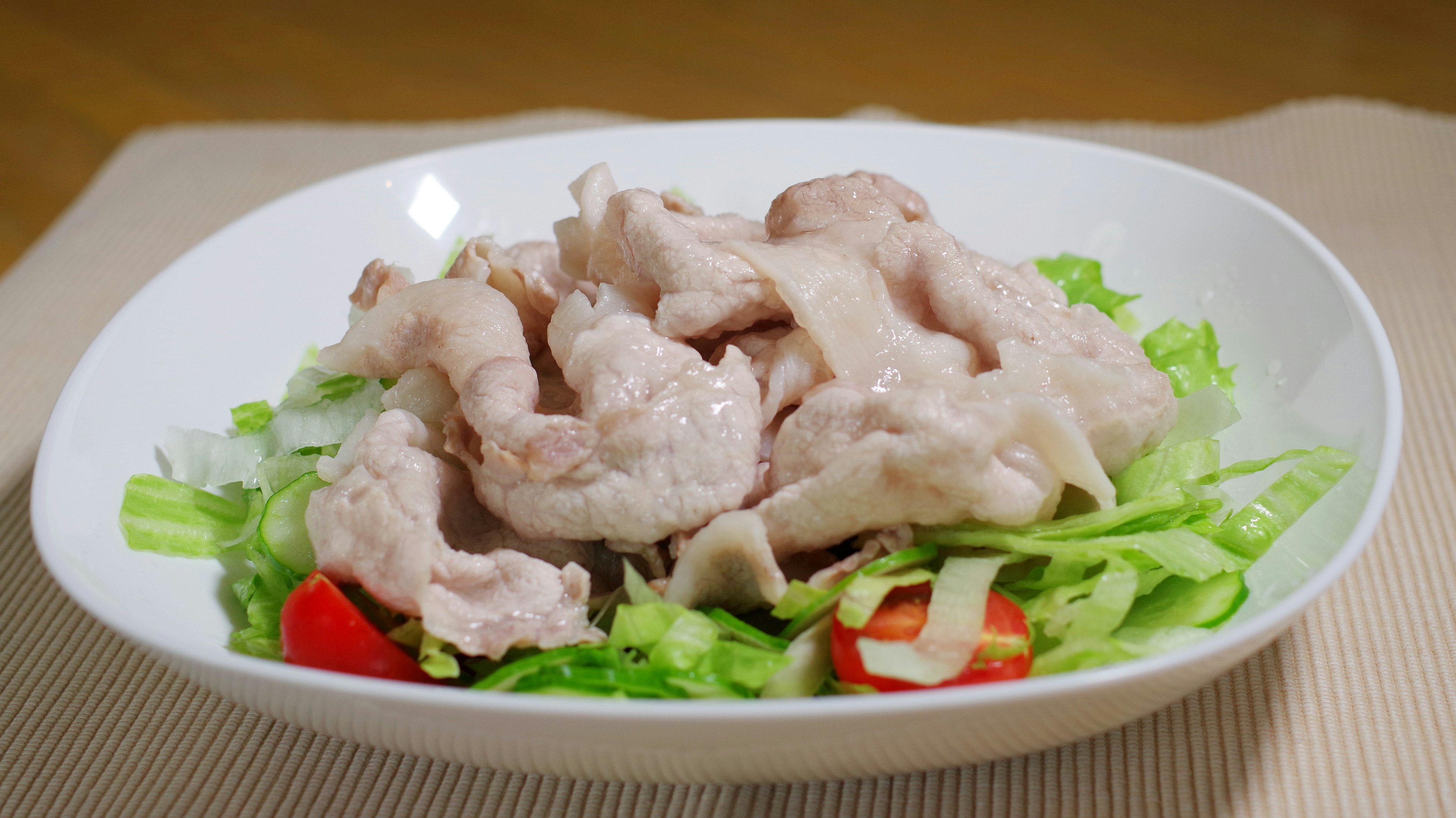 In Scheiben geschnittenes Fleisch auf einem Bett aus Salat in einem weißen Teller