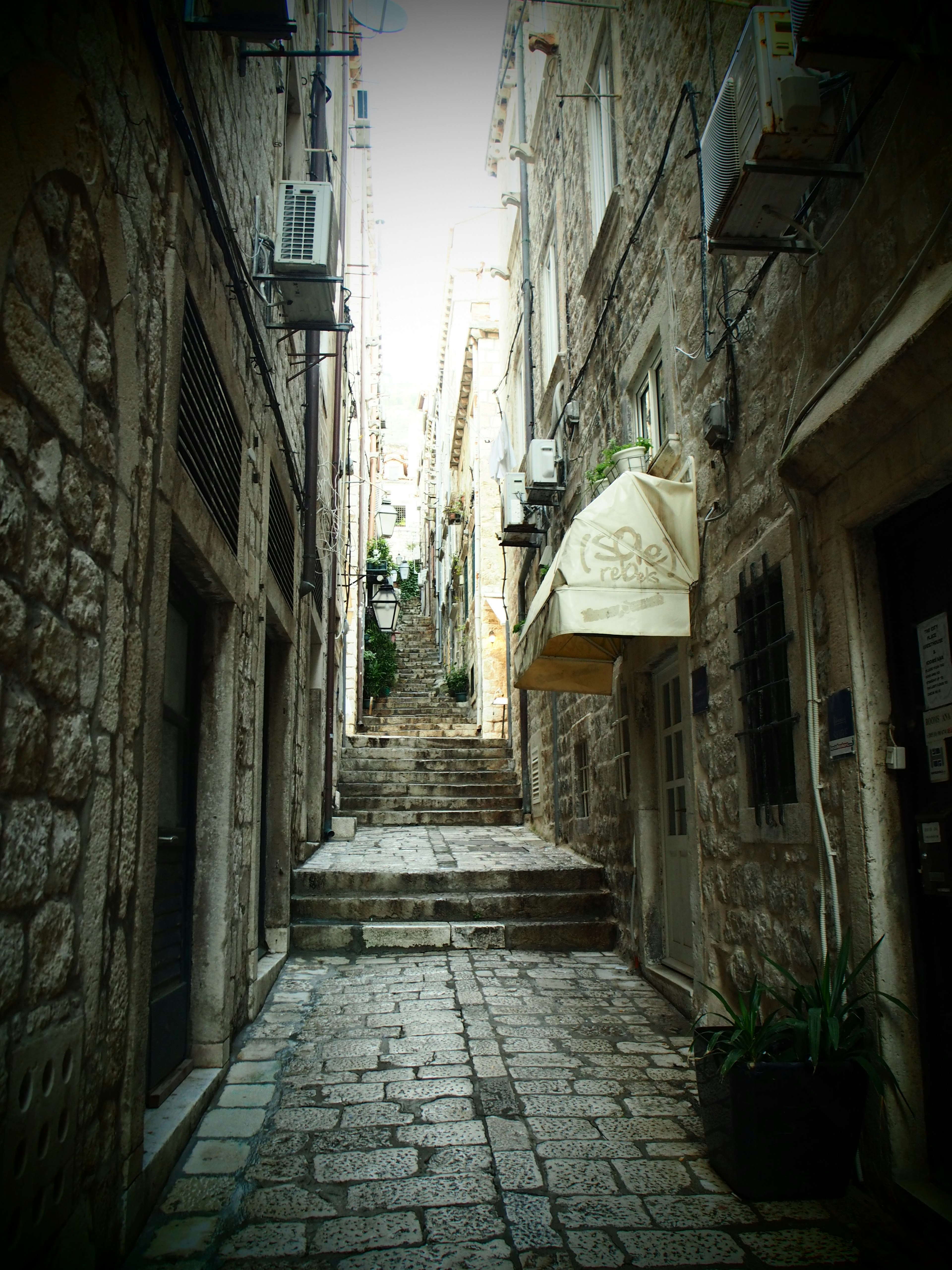 Narrow cobblestone alley with stone walls and steps leading up