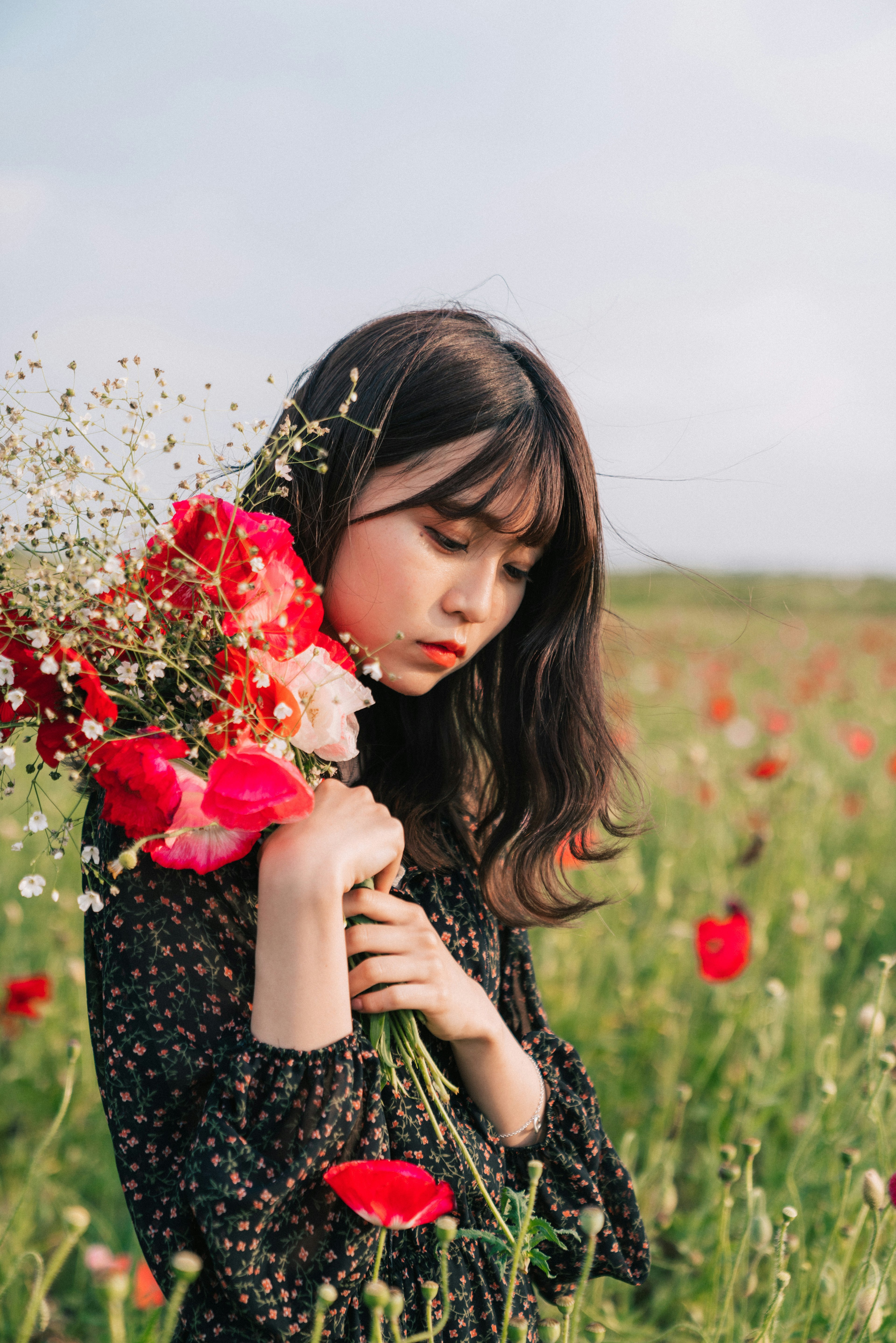 Eine Frau mit einem Blumenstrauß steht in einem weiten Blumenfeld