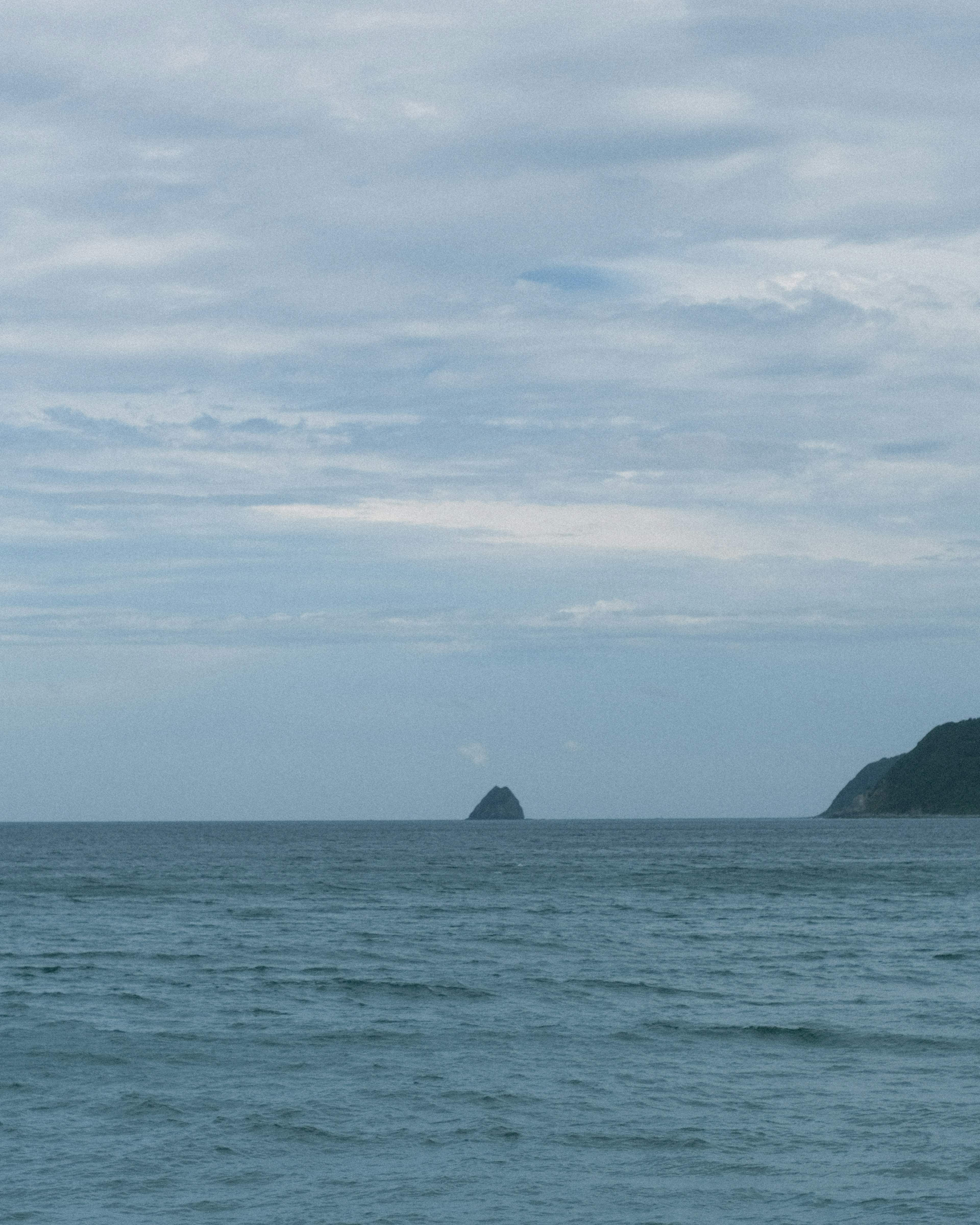 藍色海洋和多雲天空的風景 中間有一個小島