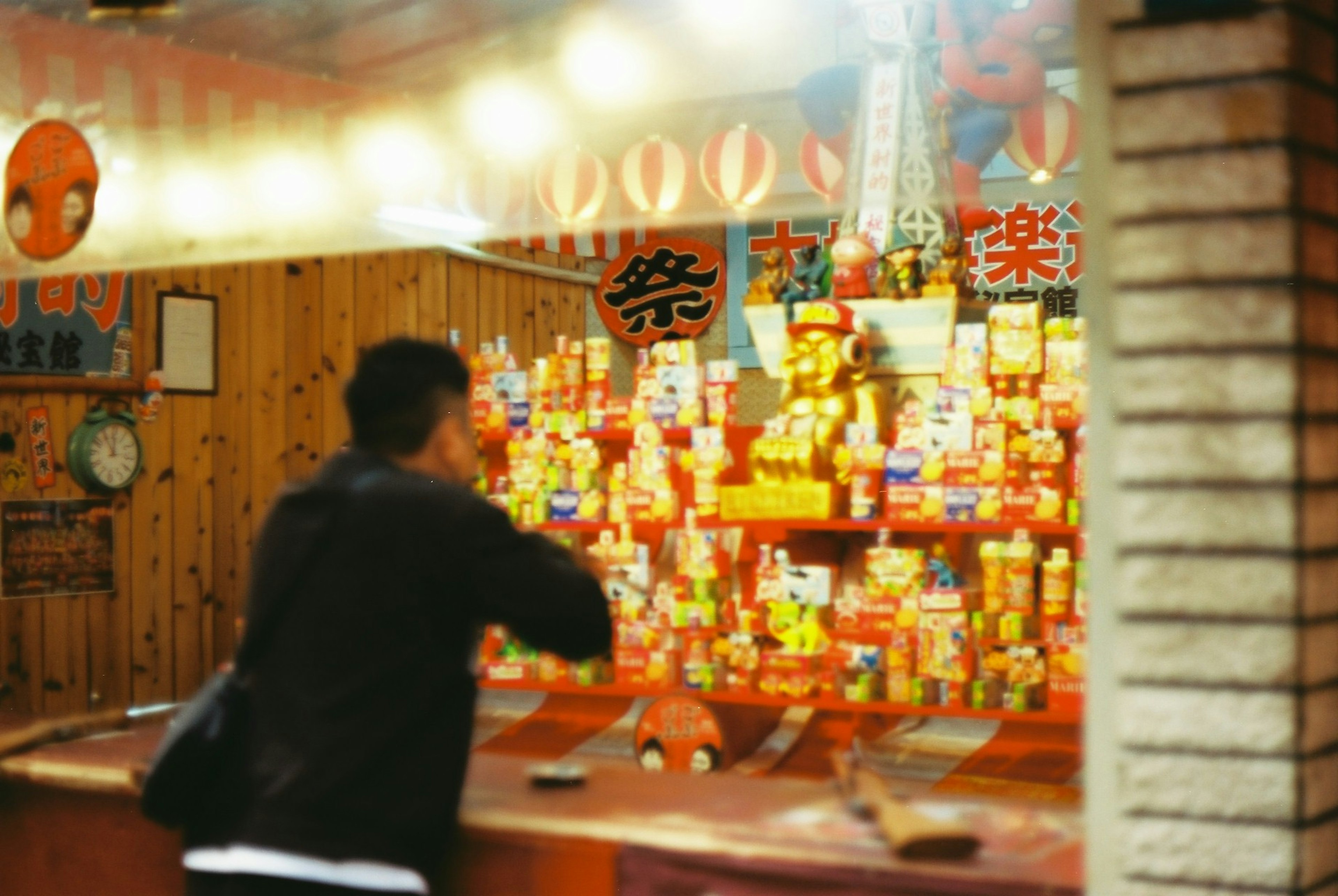 A man selecting products in front of a stall filled with colorful candy boxes