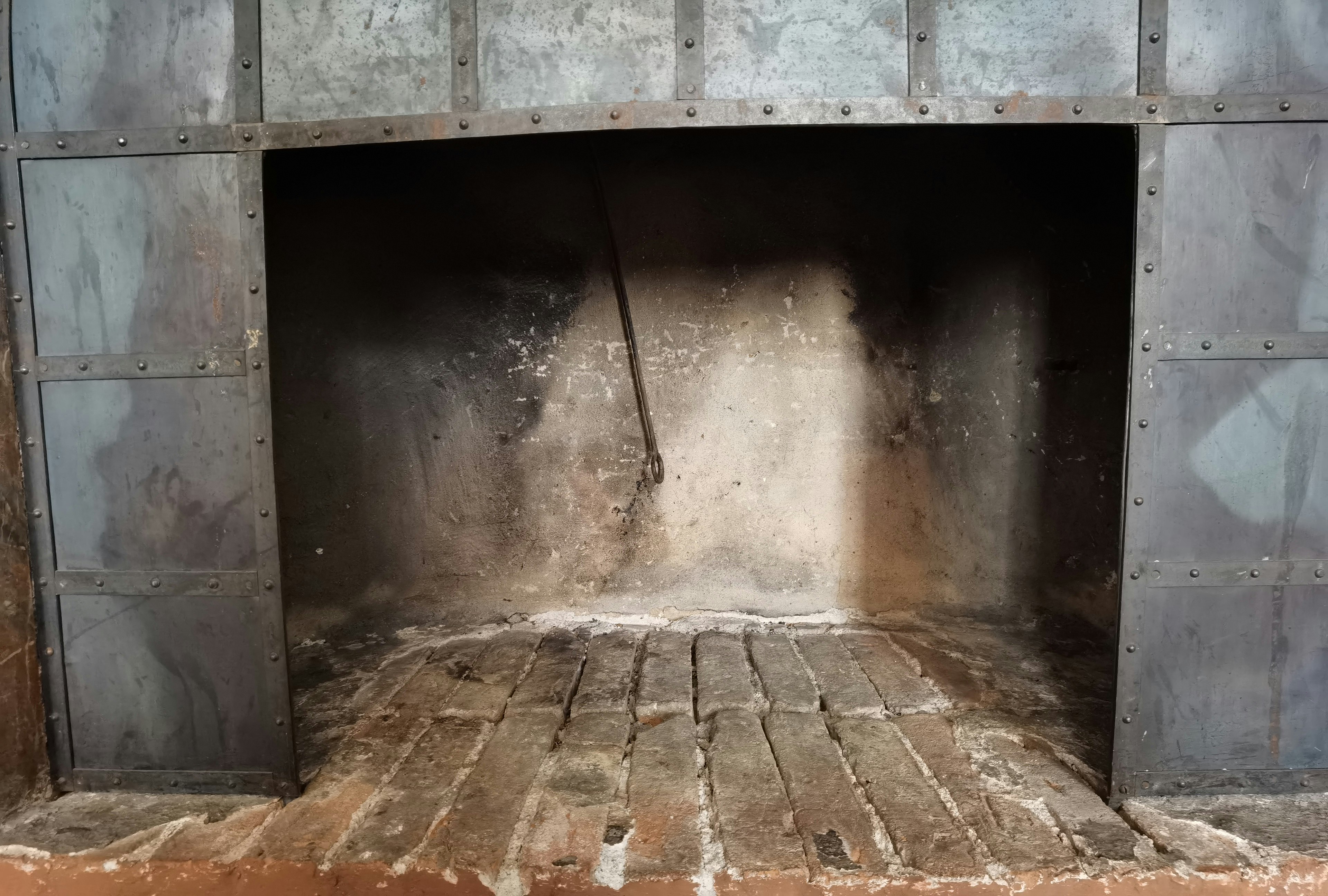 Interior de una vieja chimenea con paredes de metal y suelo de ladrillo