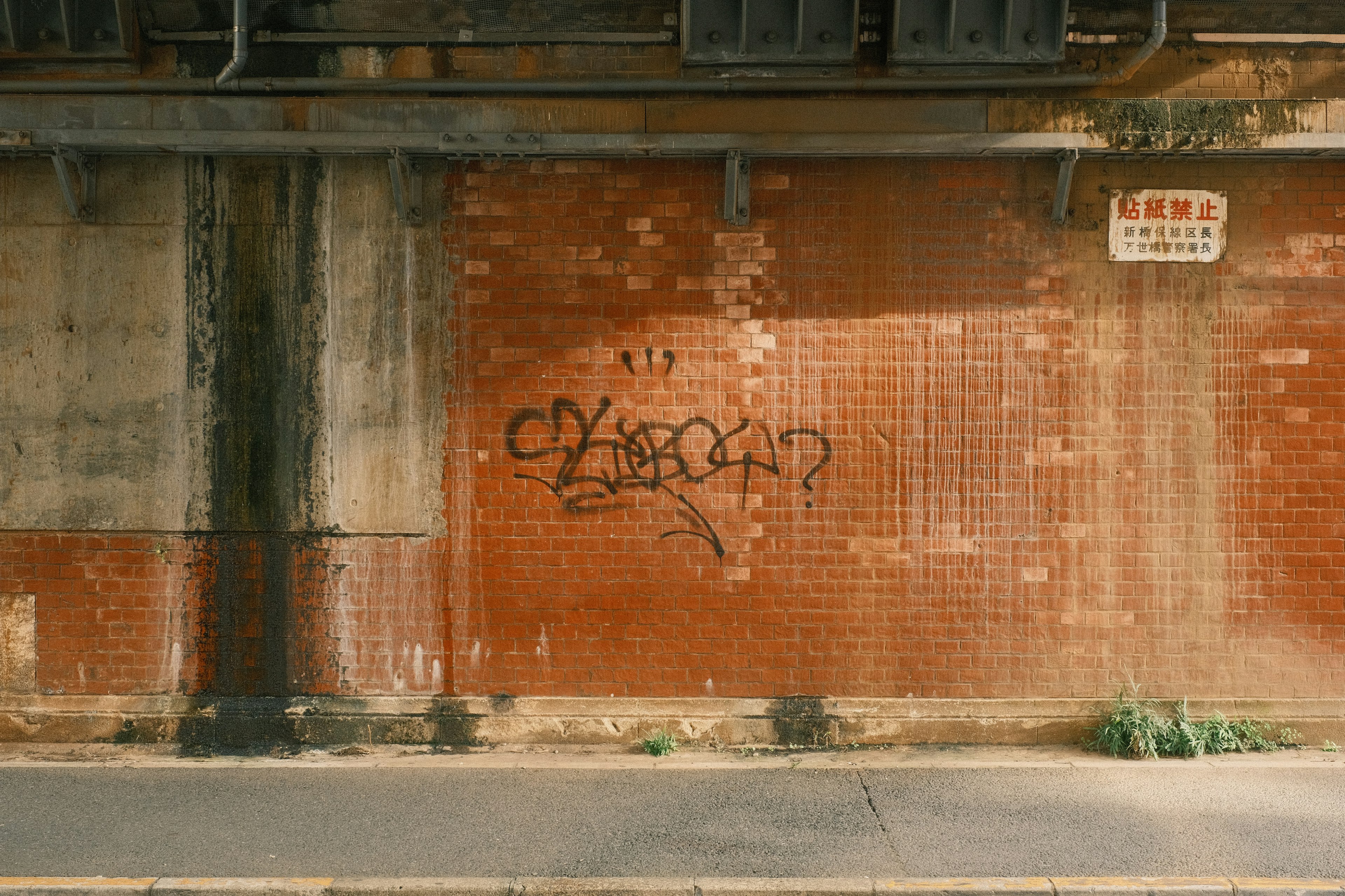 Graffiti on a red brick wall with a weathered appearance