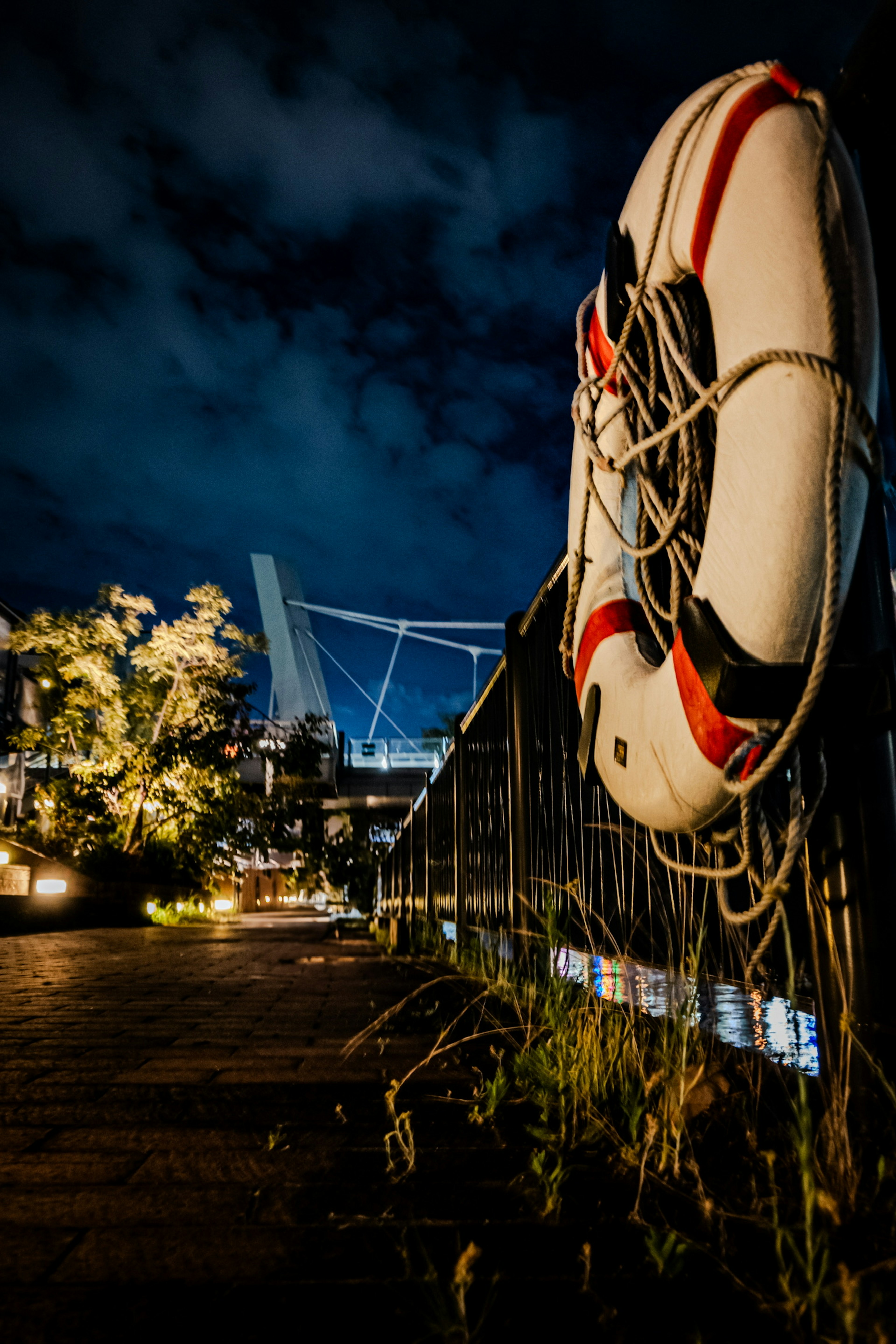 Bouée de sauvetage sur un quai la nuit avec la silhouette d'un pont en arrière-plan