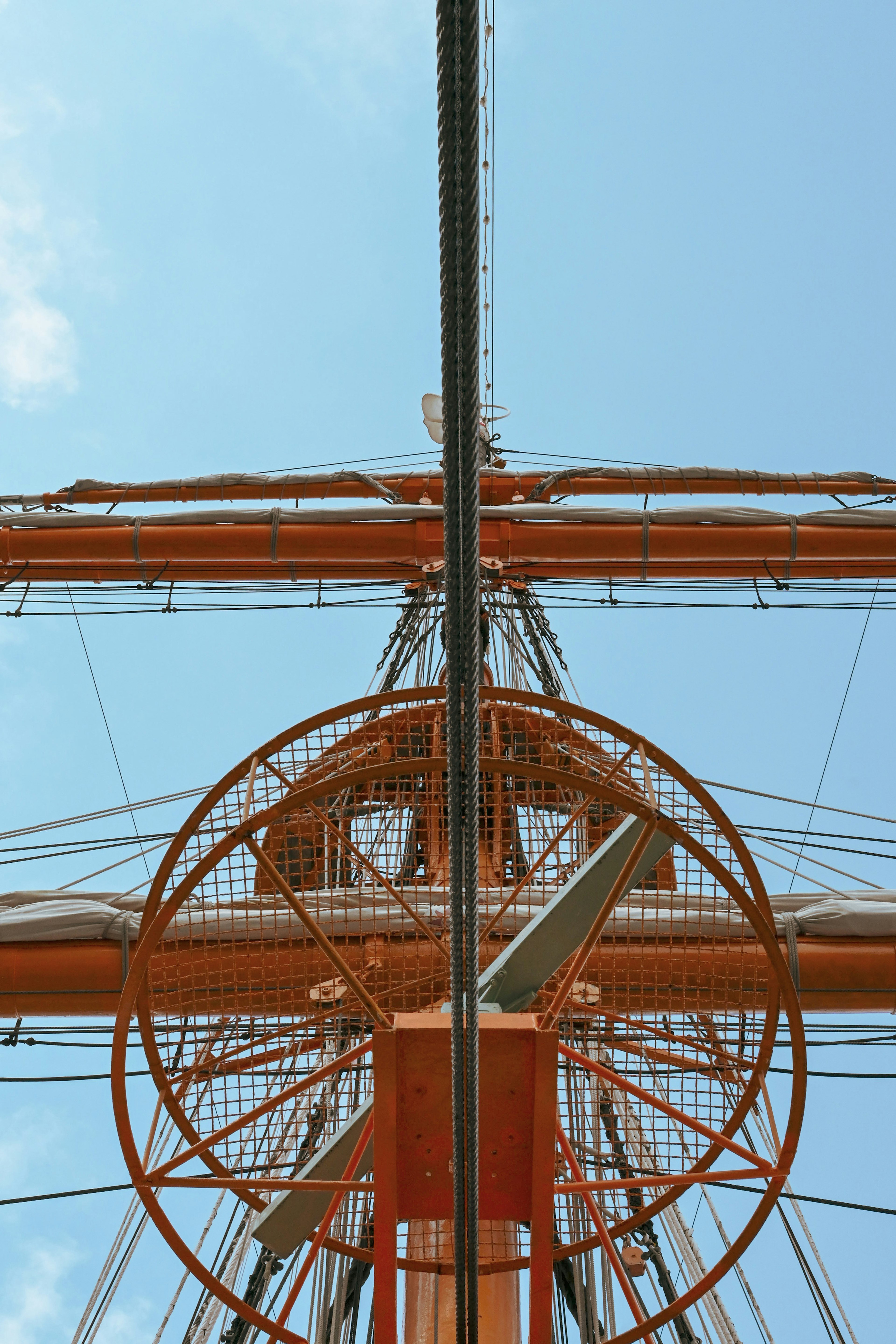 View of a ship's mast and sail structure against a blue sky