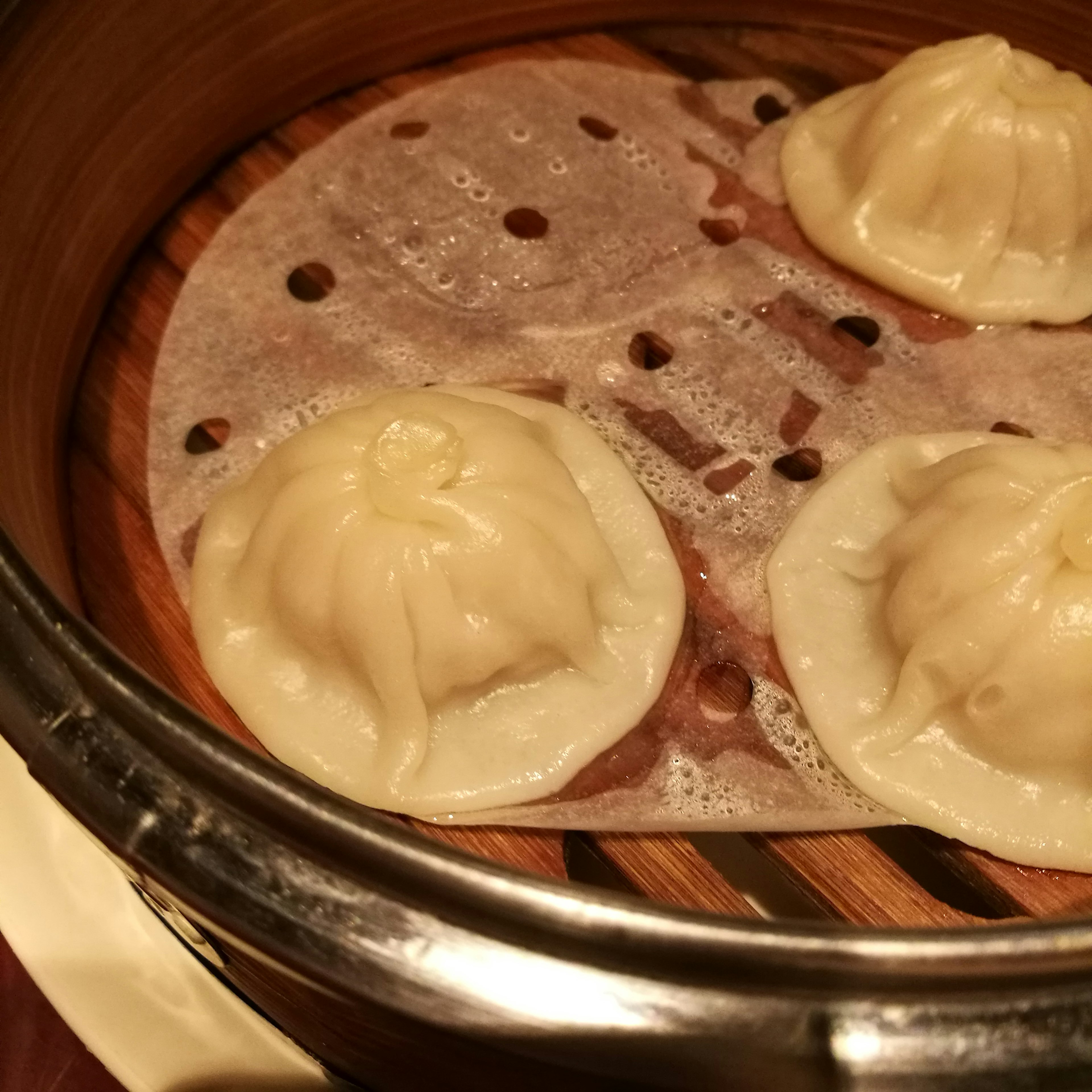 Three xiaolongbao in a bamboo steamer