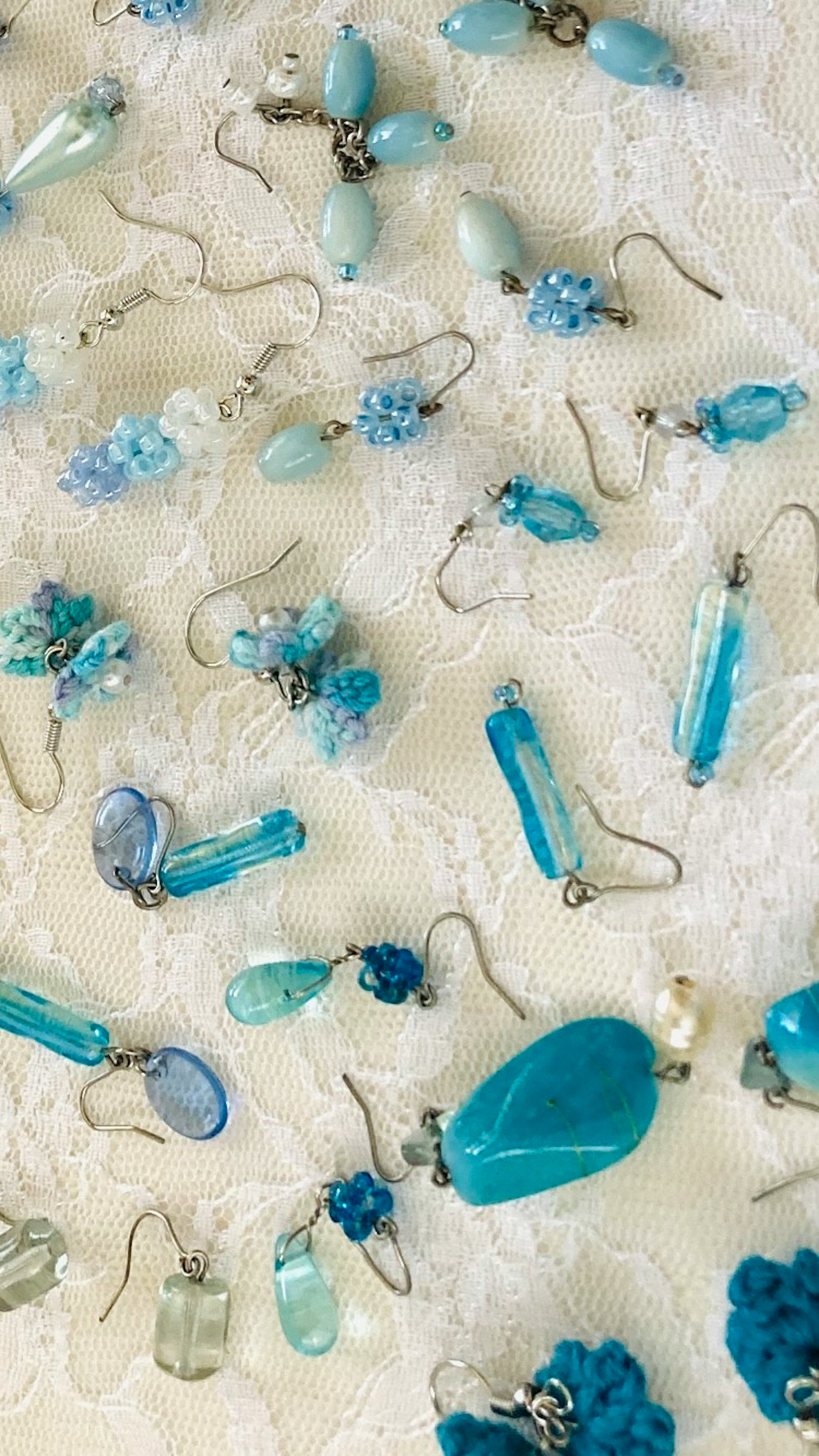 A variety of blue earrings displayed on lace fabric