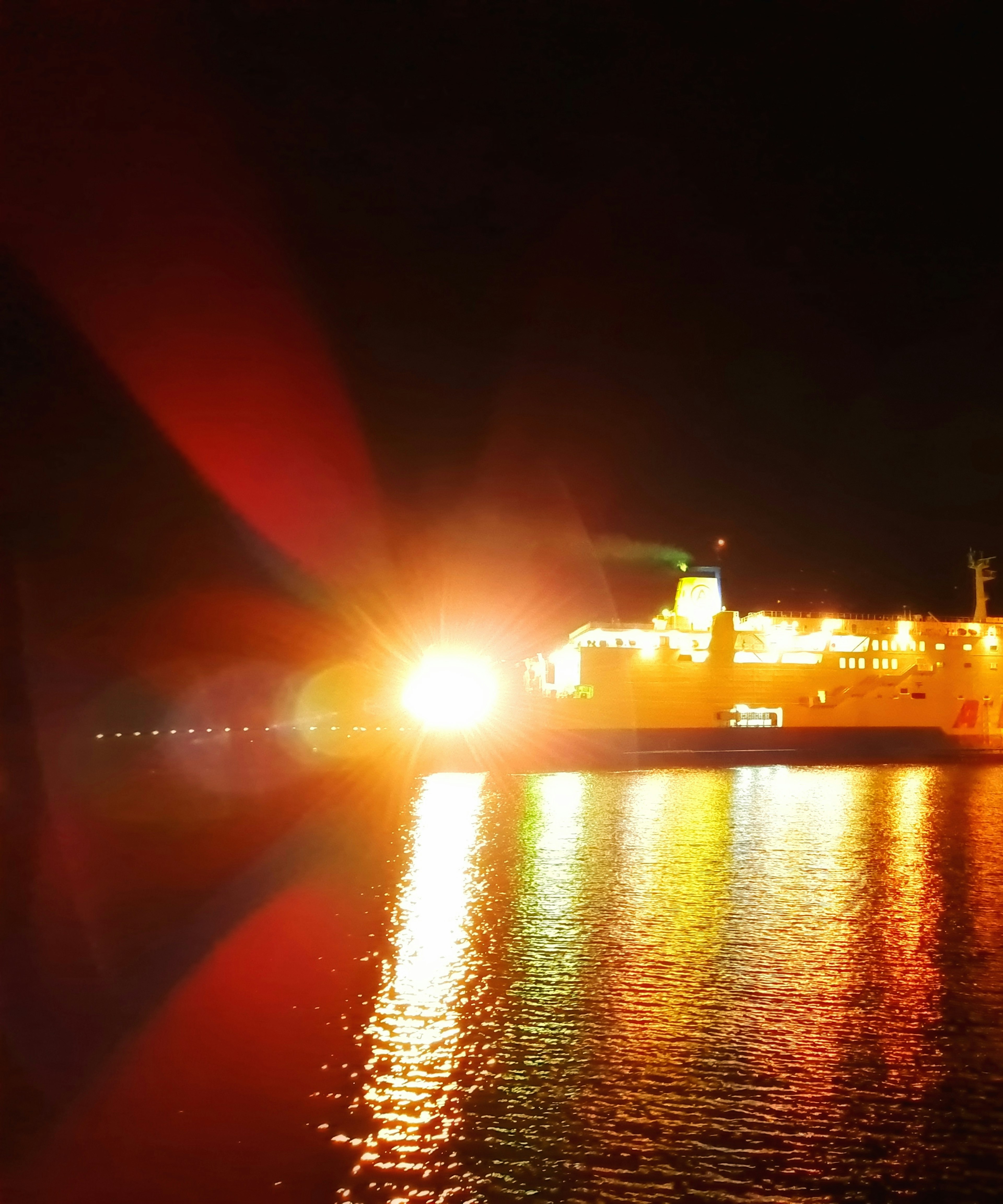 A bright ship illuminating the night sea with reflections