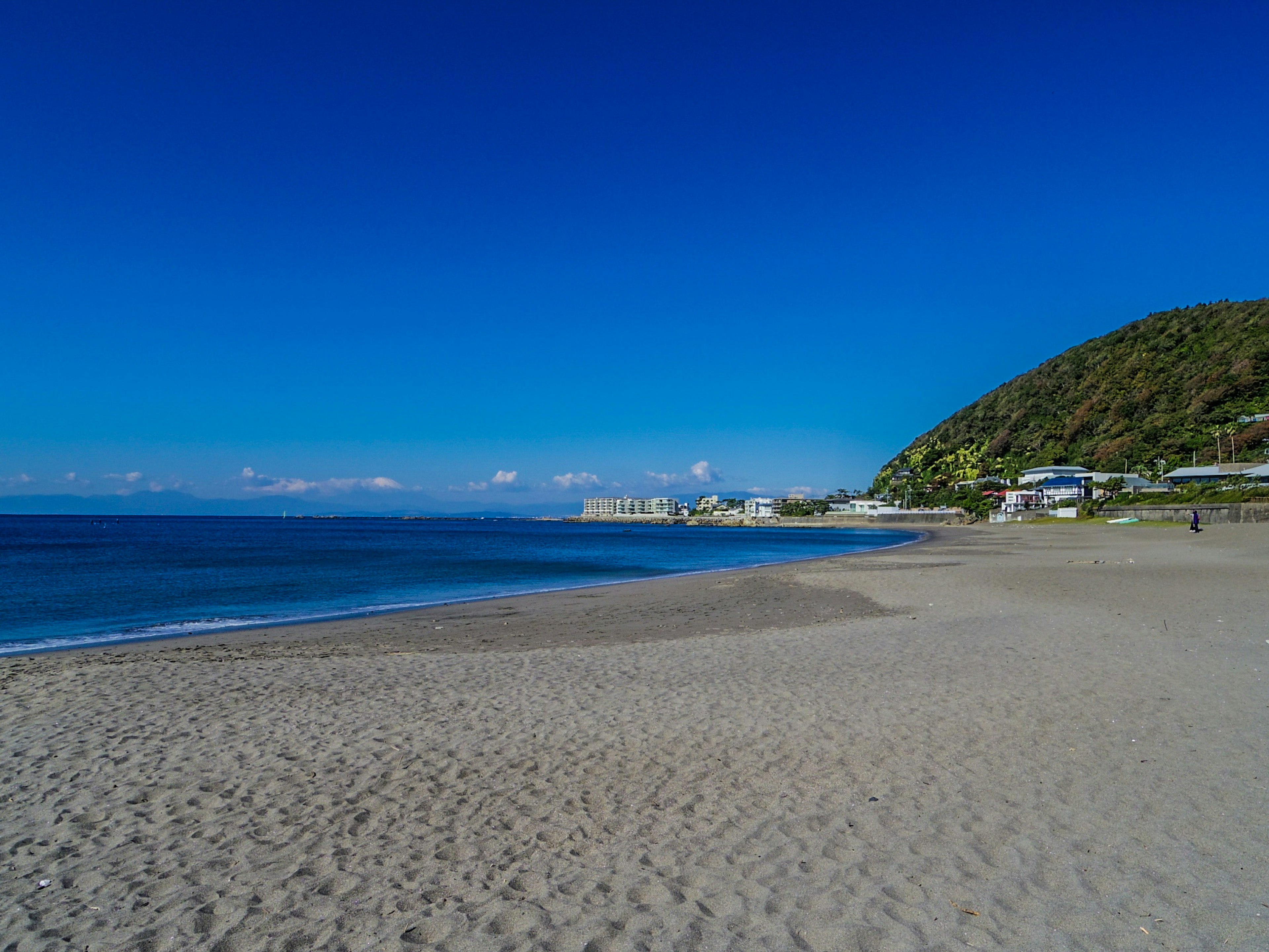 ทิวทัศน์ชายหาดที่เงียบสงบล้อมรอบด้วยทะเลและท้องฟ้าสีฟ้า