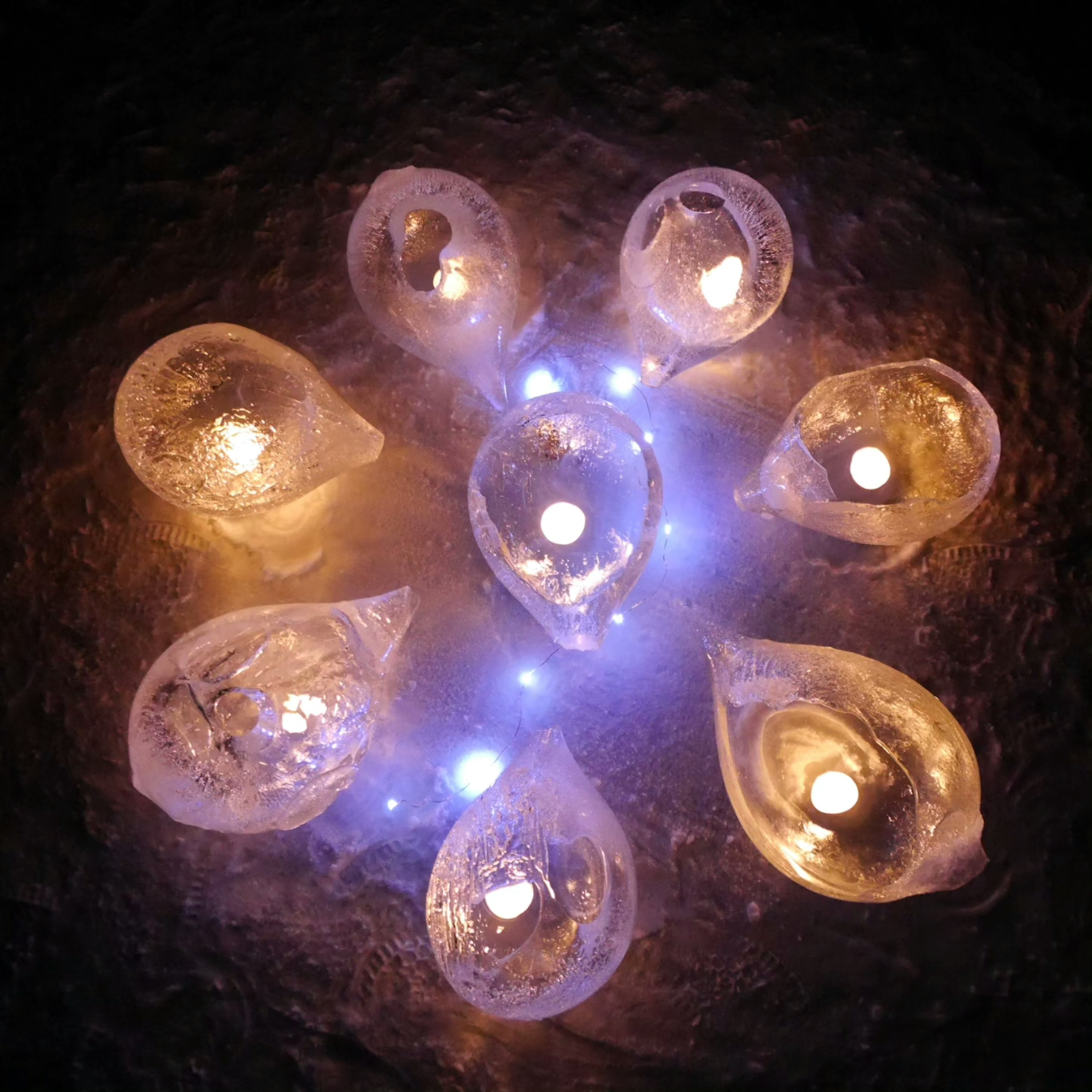 Illuminated teardrop-shaped candles arranged in a circular pattern