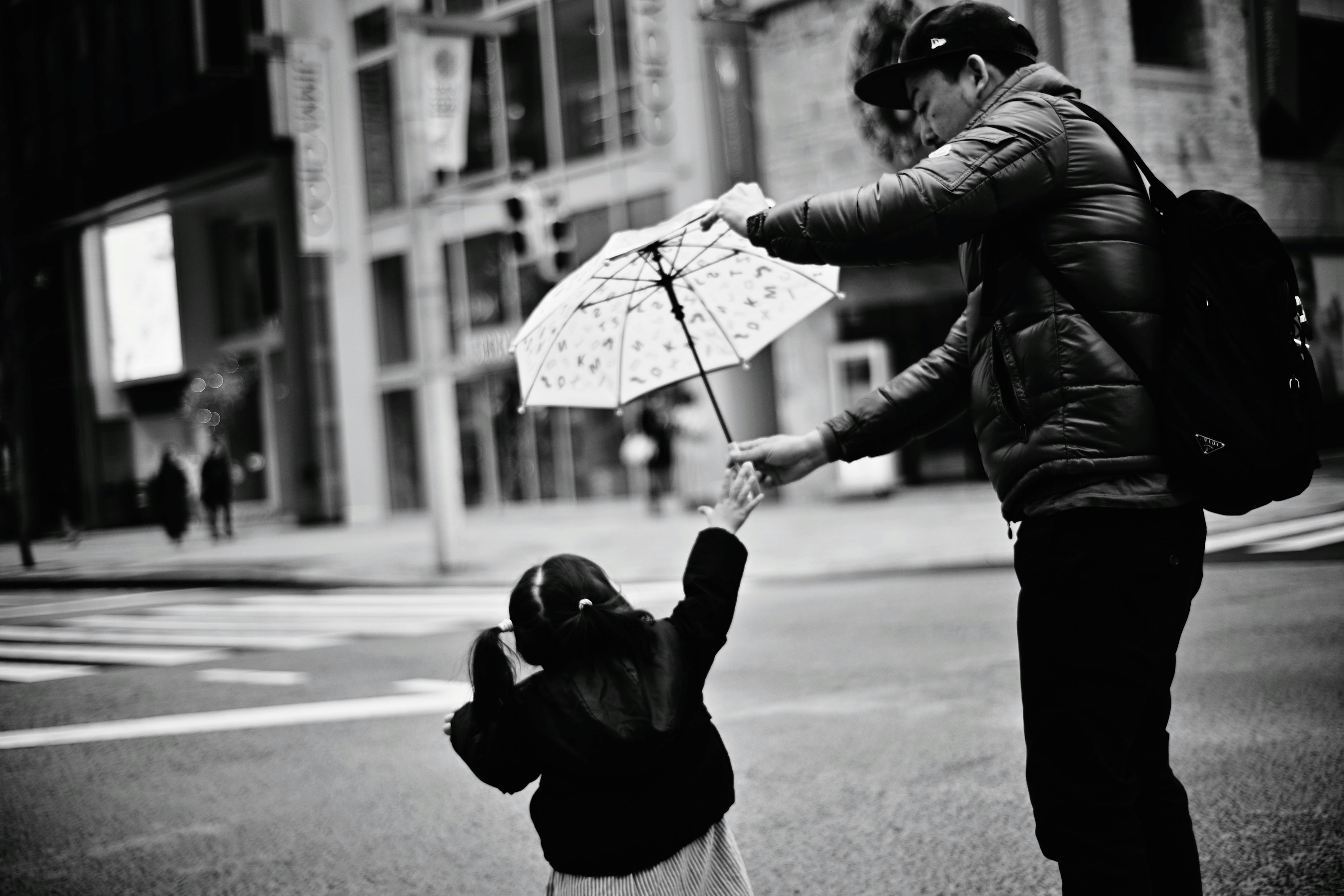 Photo en noir et blanc d'un adulte tenant un parapluie et tenant la main d'un enfant sous la pluie