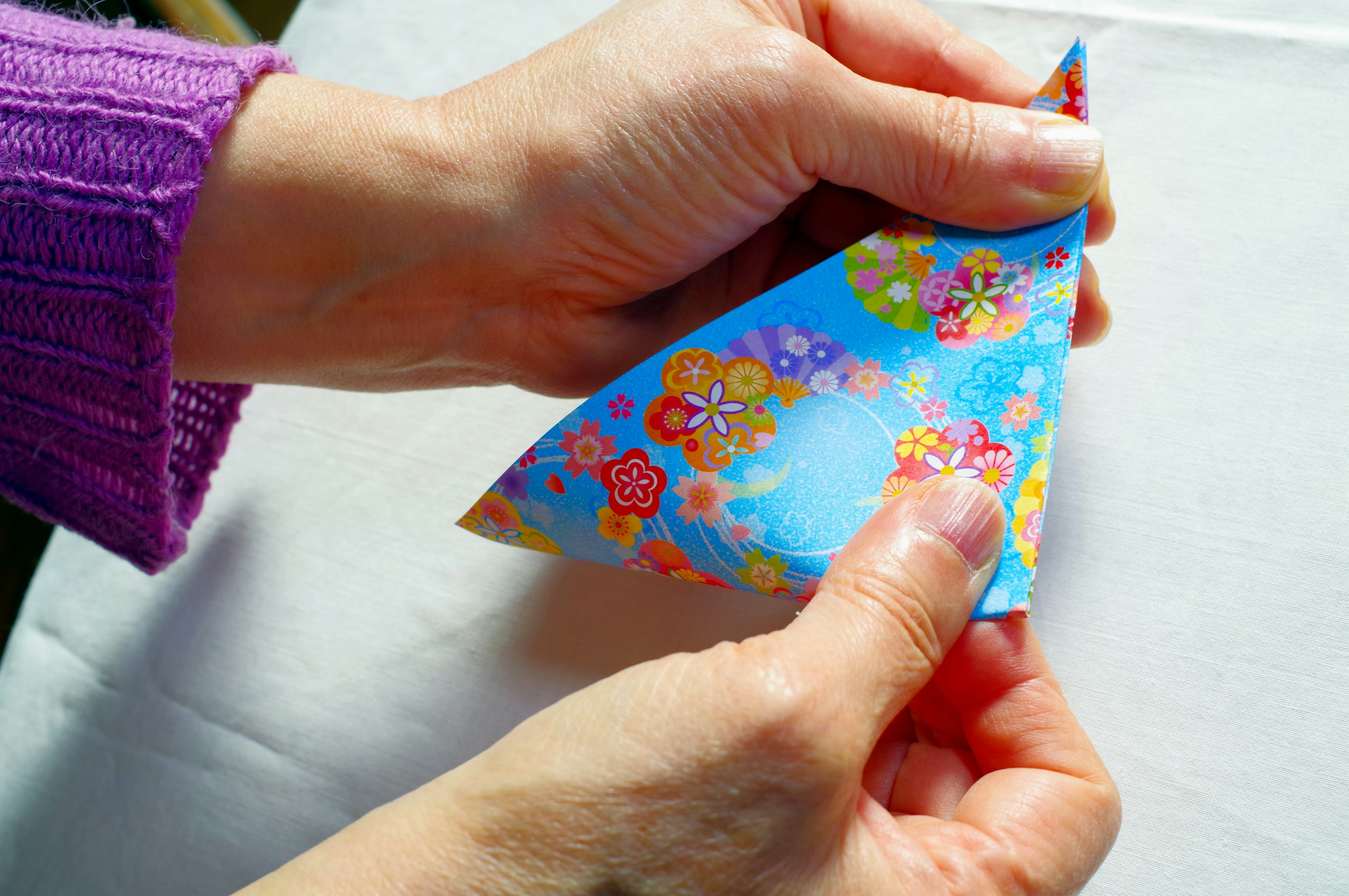 Mains pliant du papier origami coloré à motifs