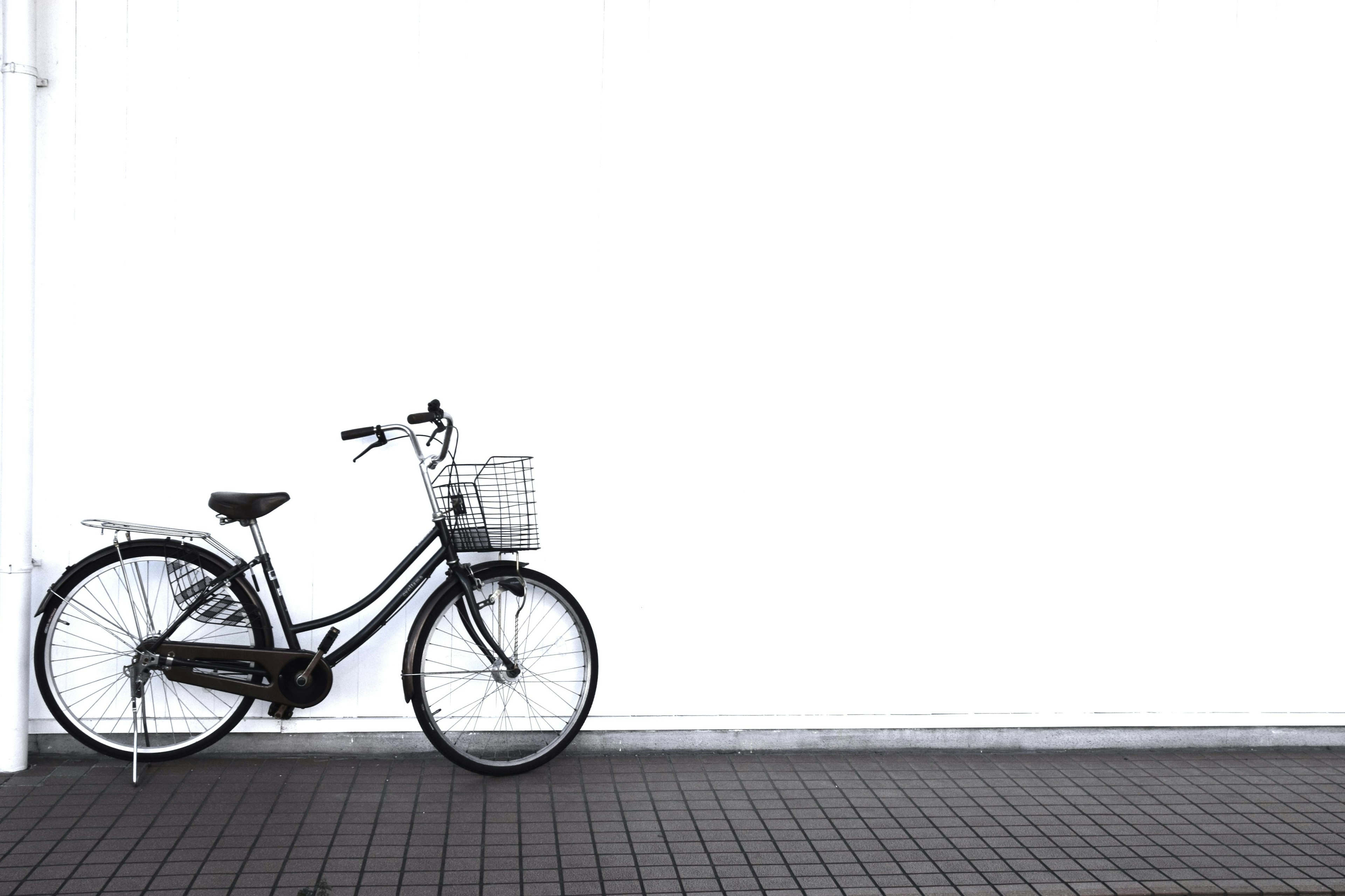 Bicicleta negra apoyada contra una pared blanca