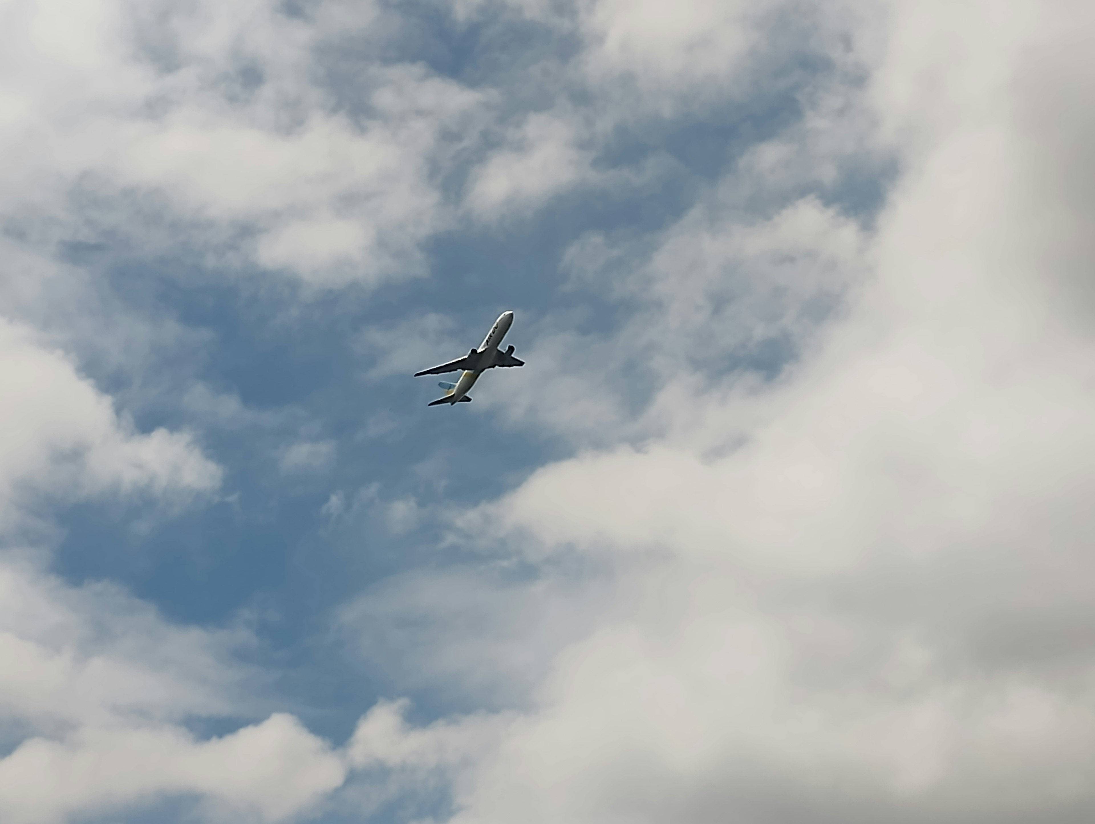 Avión volando en el cielo azul con nubes blancas