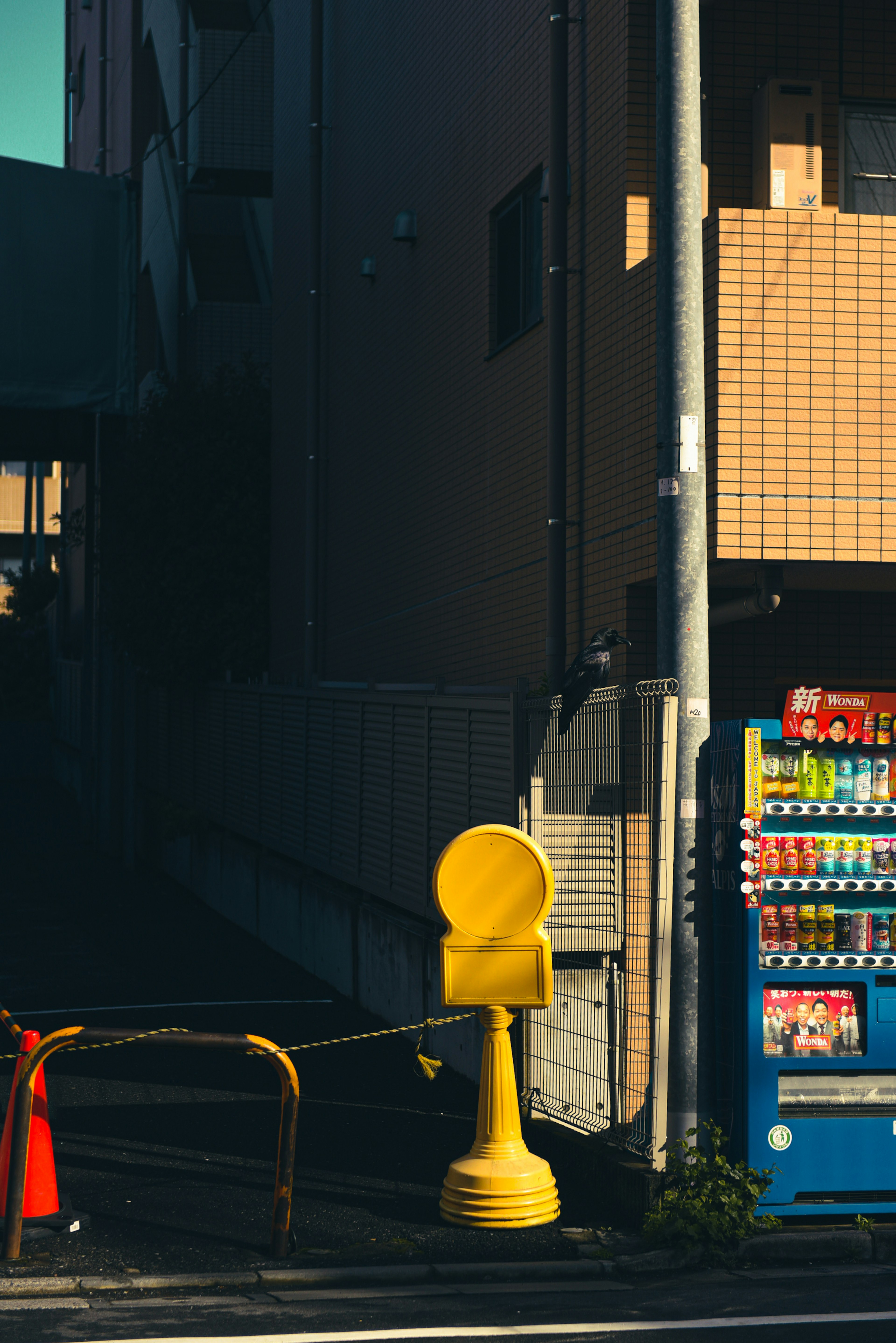 Esquina de la calle con un buzón amarillo y una máquina expendedora